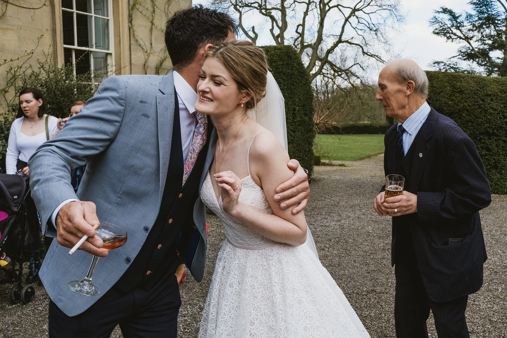 Bride hugs guest at outdoor wedding reception.