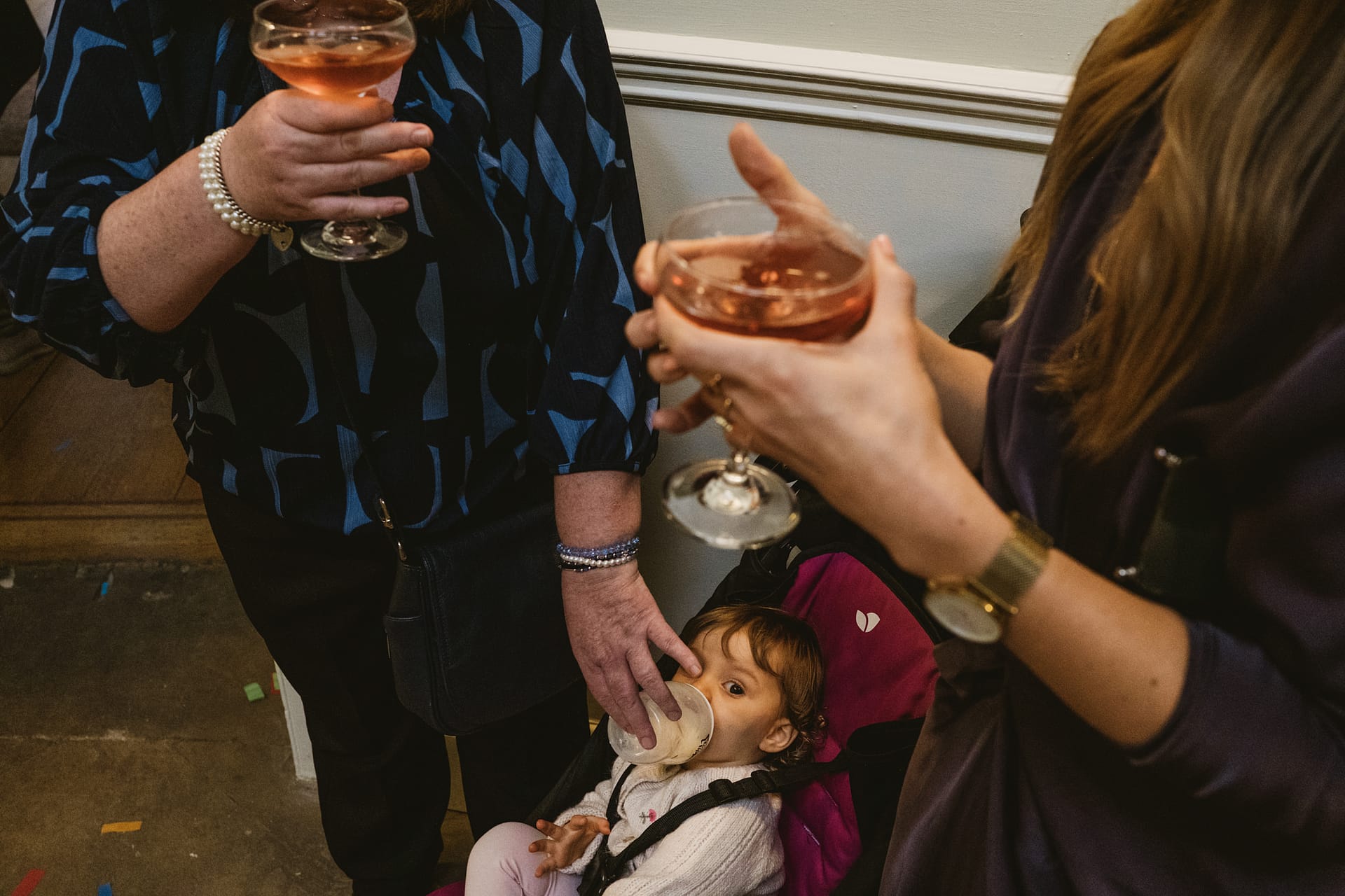 Child in stroller with drink, adults holding glasses.