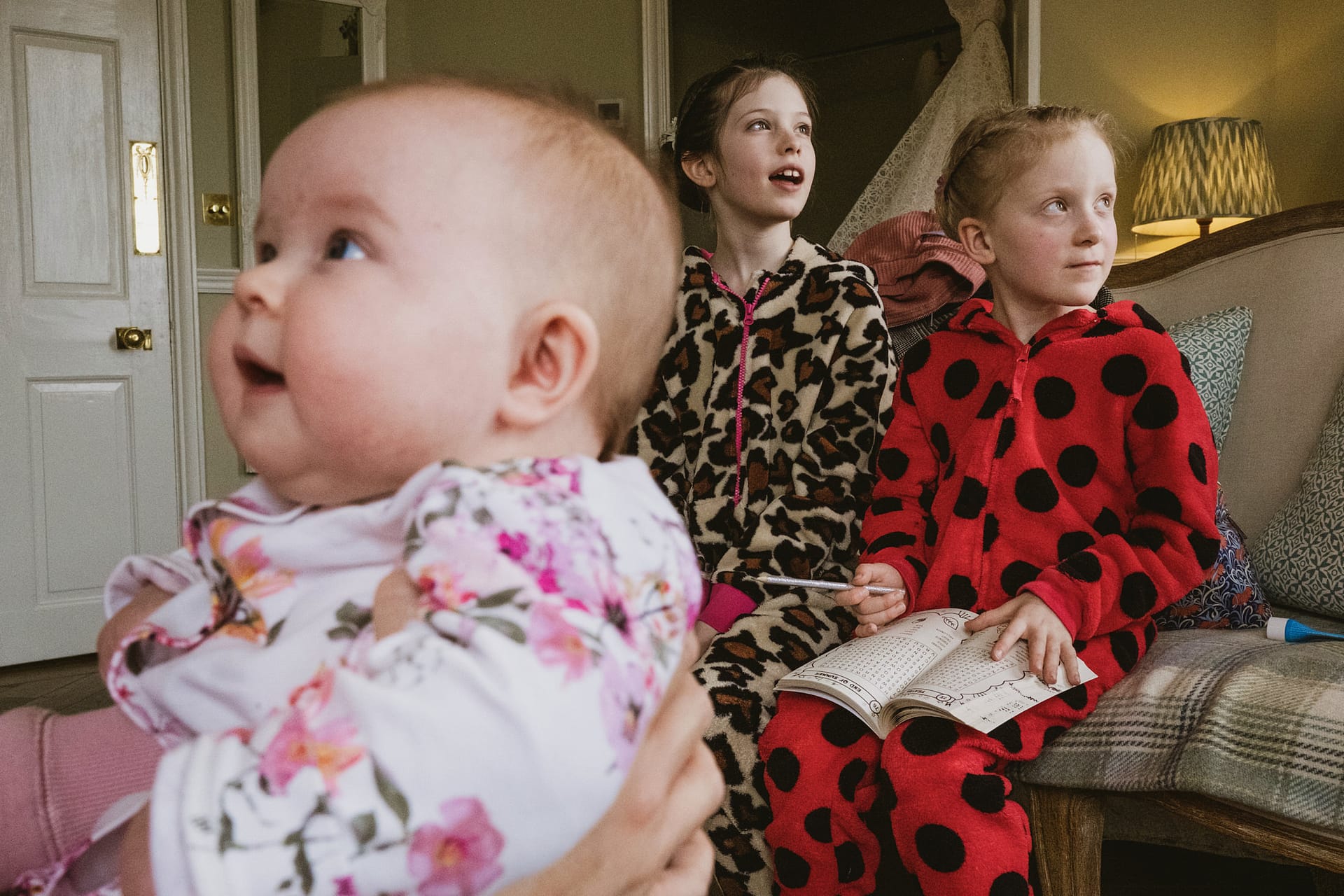 Three children in animal onesies on a sofa.