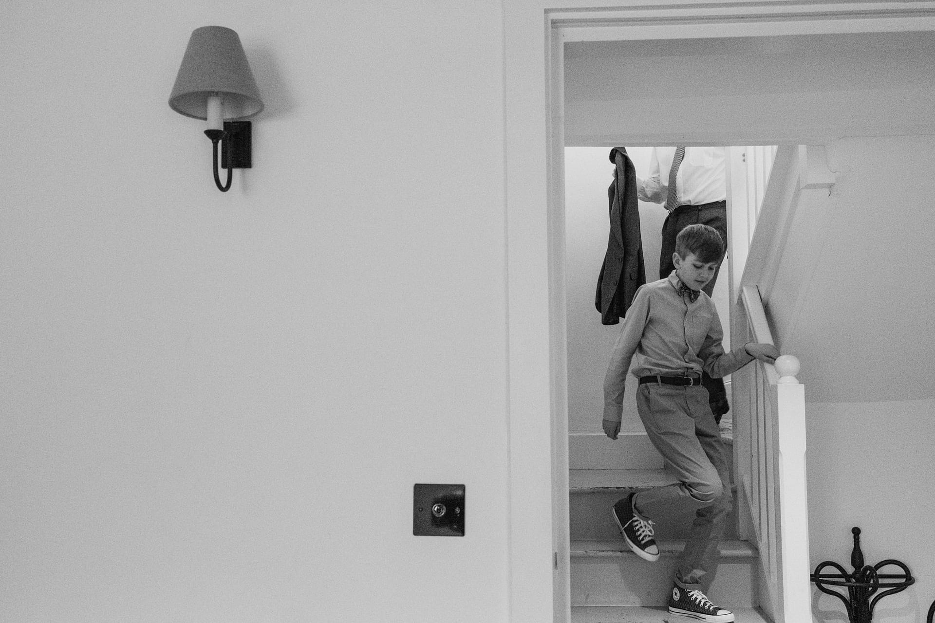 Child walking down staircase, monochrome photograph.