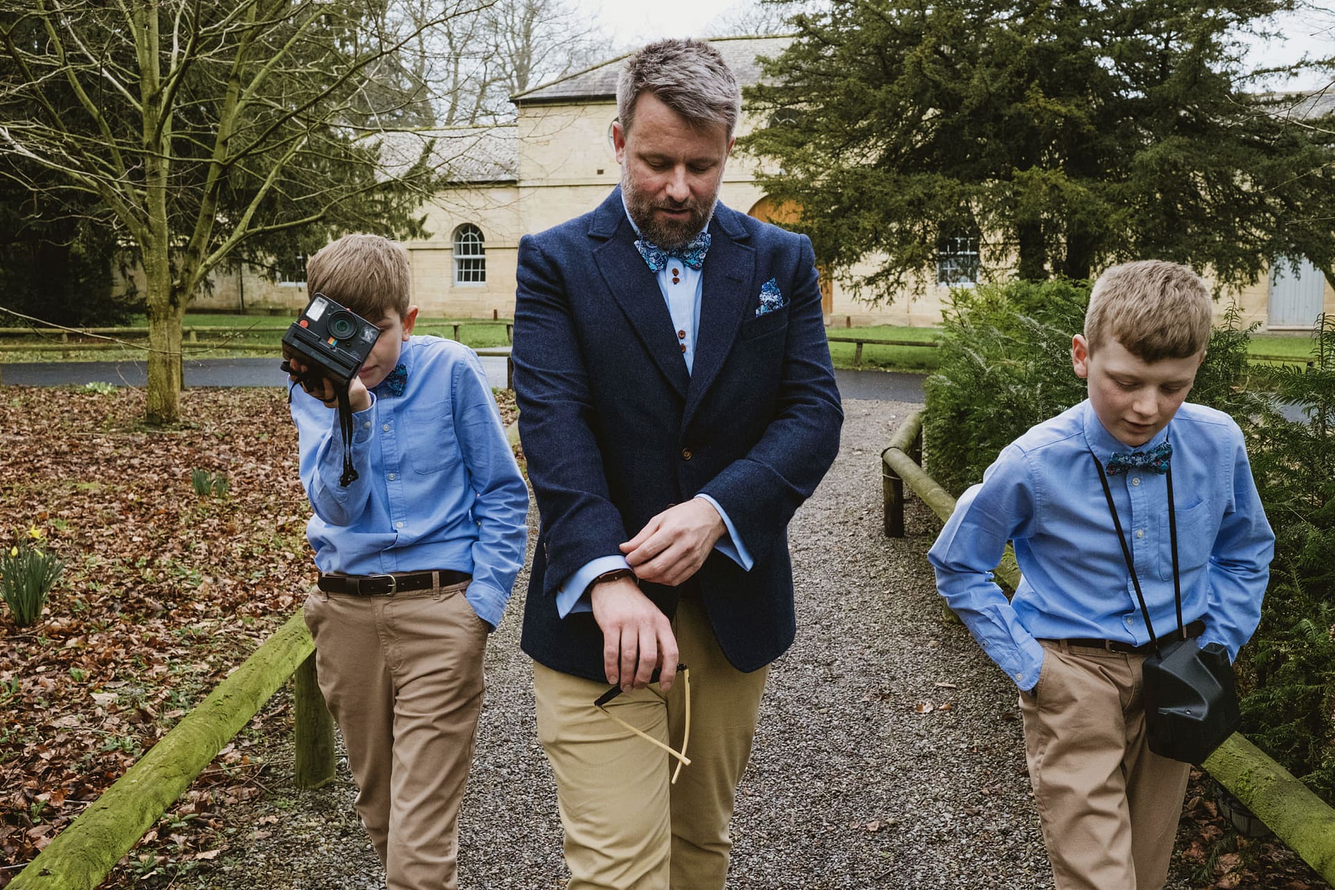 Man with children, one taking photos outdoors.