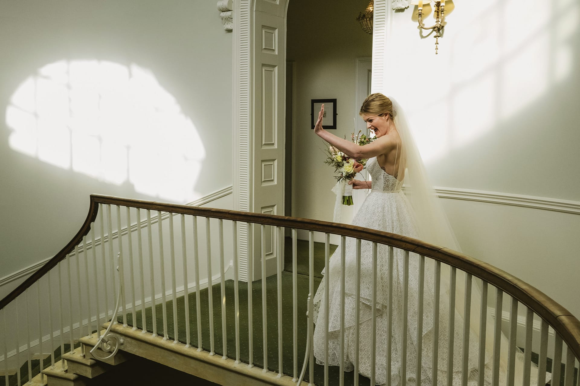 Bride holding flowers walking down staircase