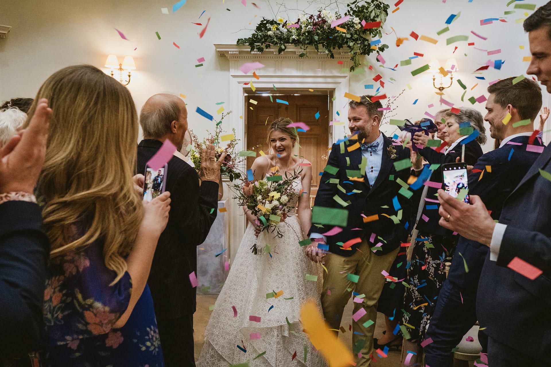 Bride and groom surrounded by colourful confetti celebration.