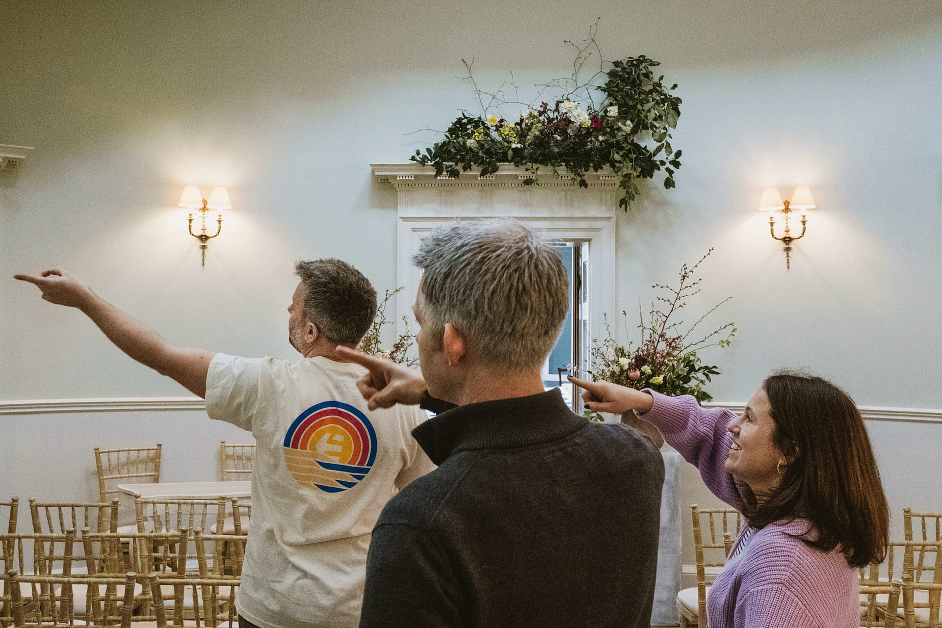 Three people pointing in a decorated room.