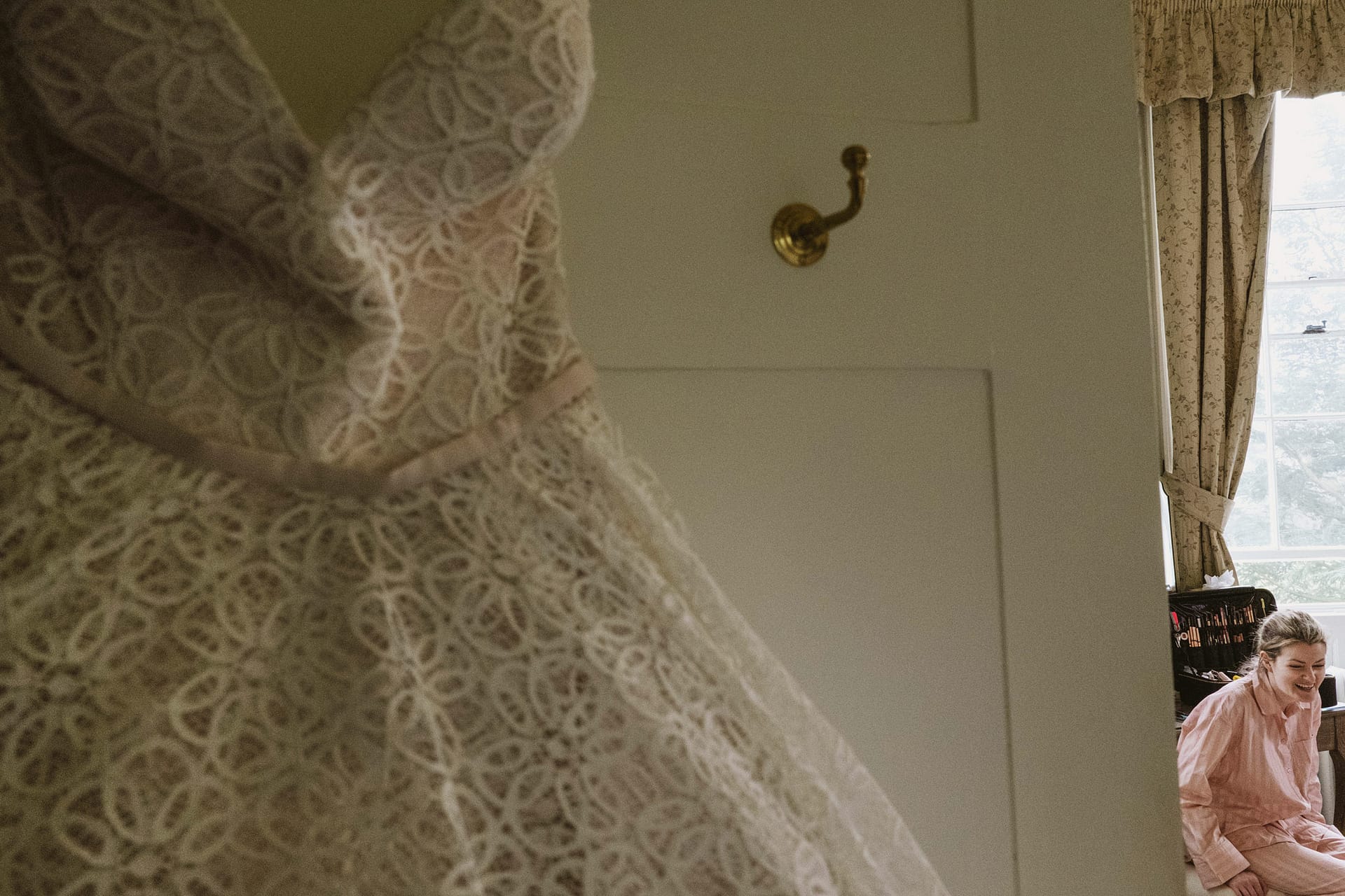 Bride laughing beside hanging wedding dress