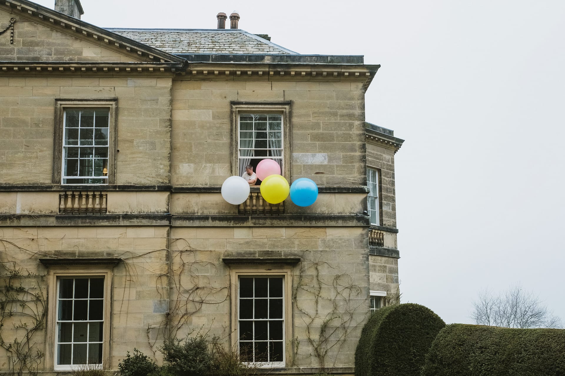 Colourful balloons outside mansion window