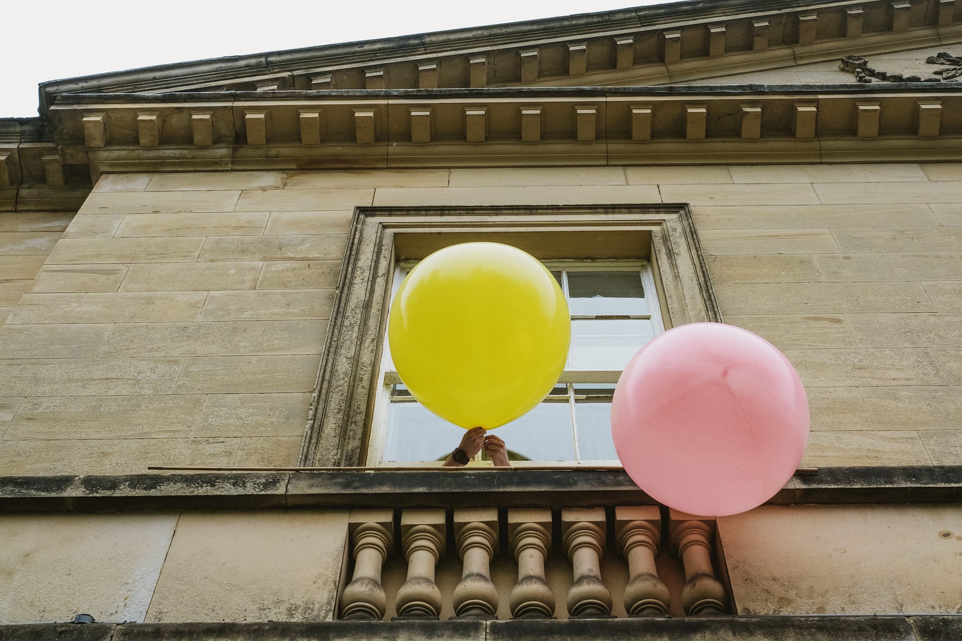 Yellow and pink balloons by a window.