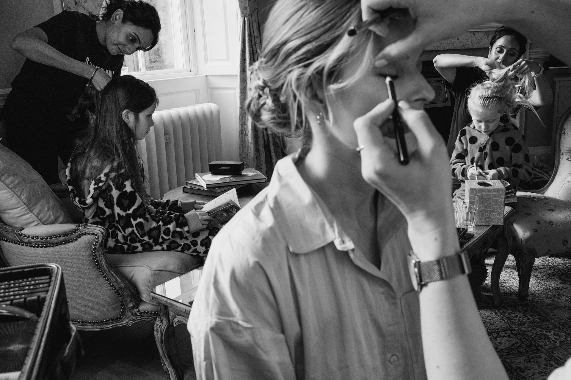 People preparing hair and makeup in living room.