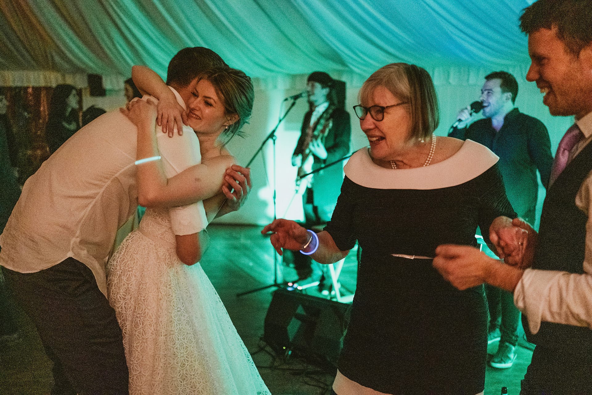 Wedding celebration with people dancing and hugging.