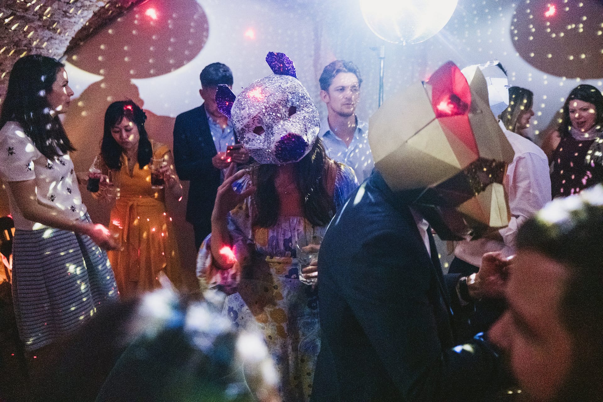 Partygoers wearing animal masks, dancing under disco lights.