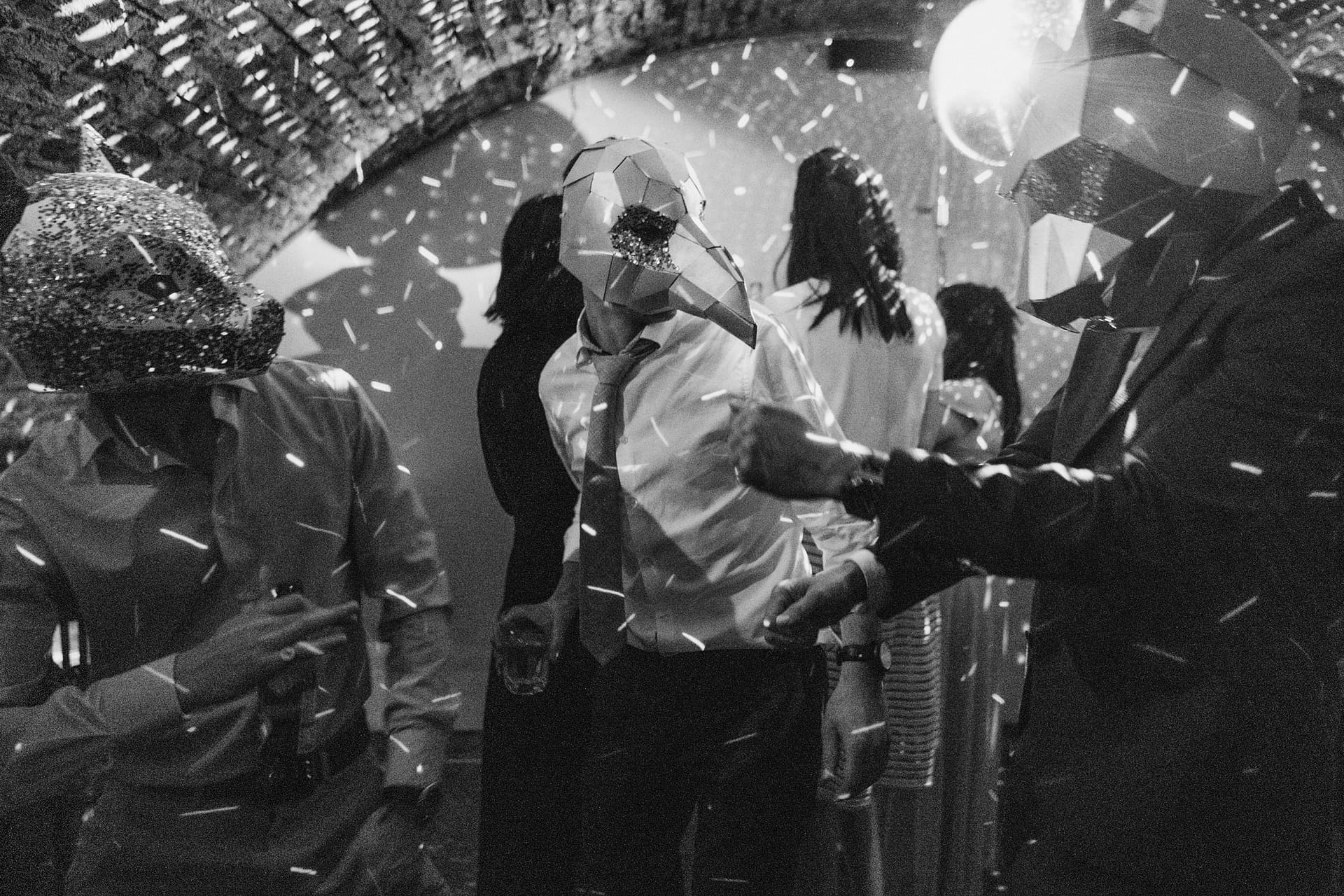 Masked partygoers dancing under disco lights.