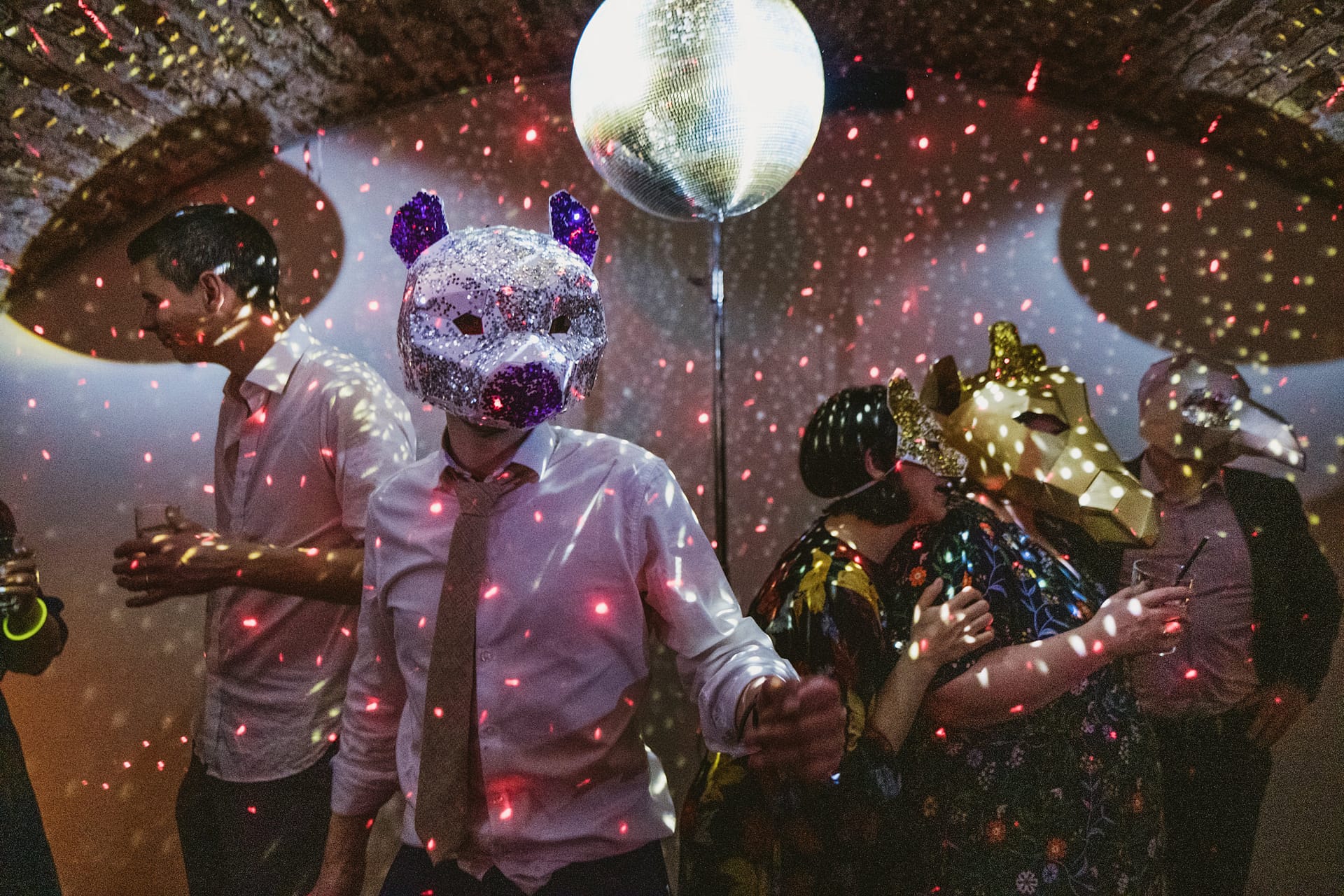 Masked partygoers dance under disco lights