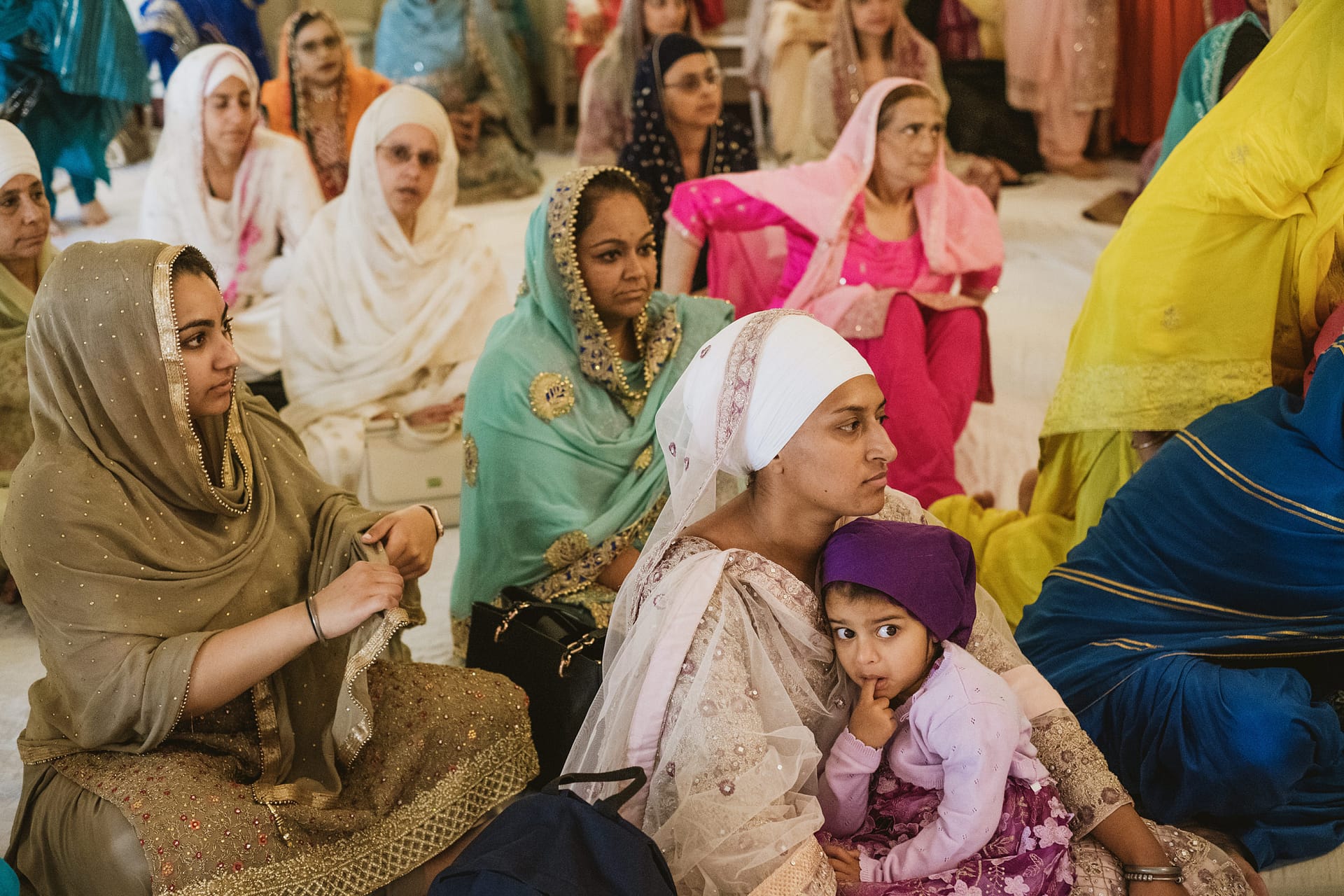 Women in traditional clothing sit during religious gathering.