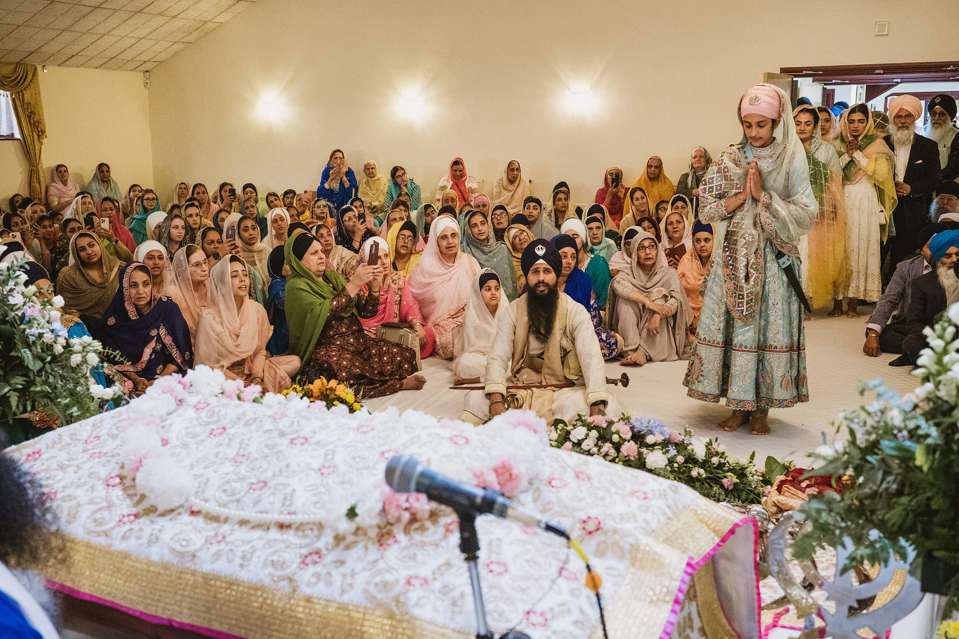 Sikh religious ceremony with attendees in vibrant attire.