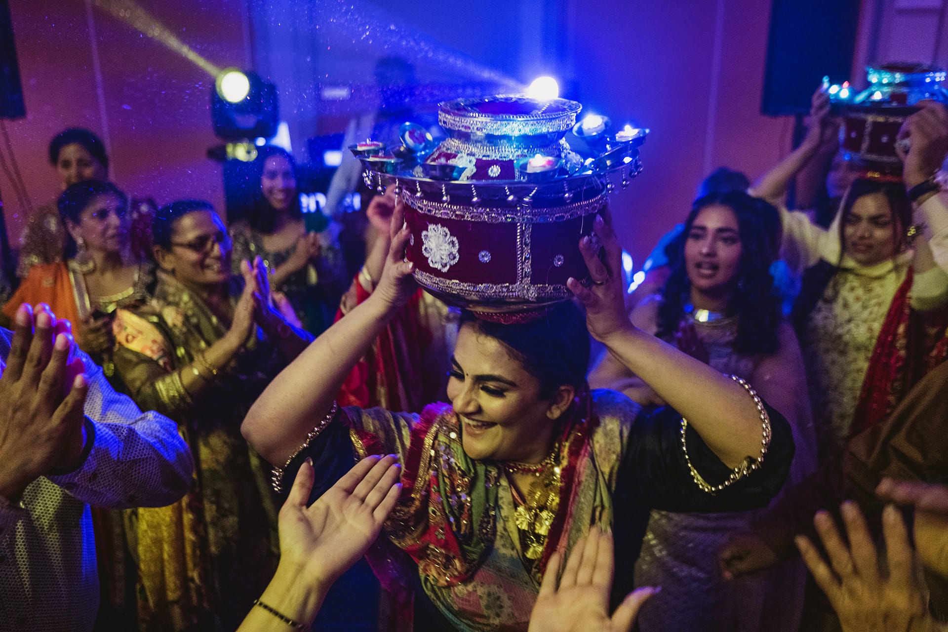 Women dancing with lit pots on heads at celebration.