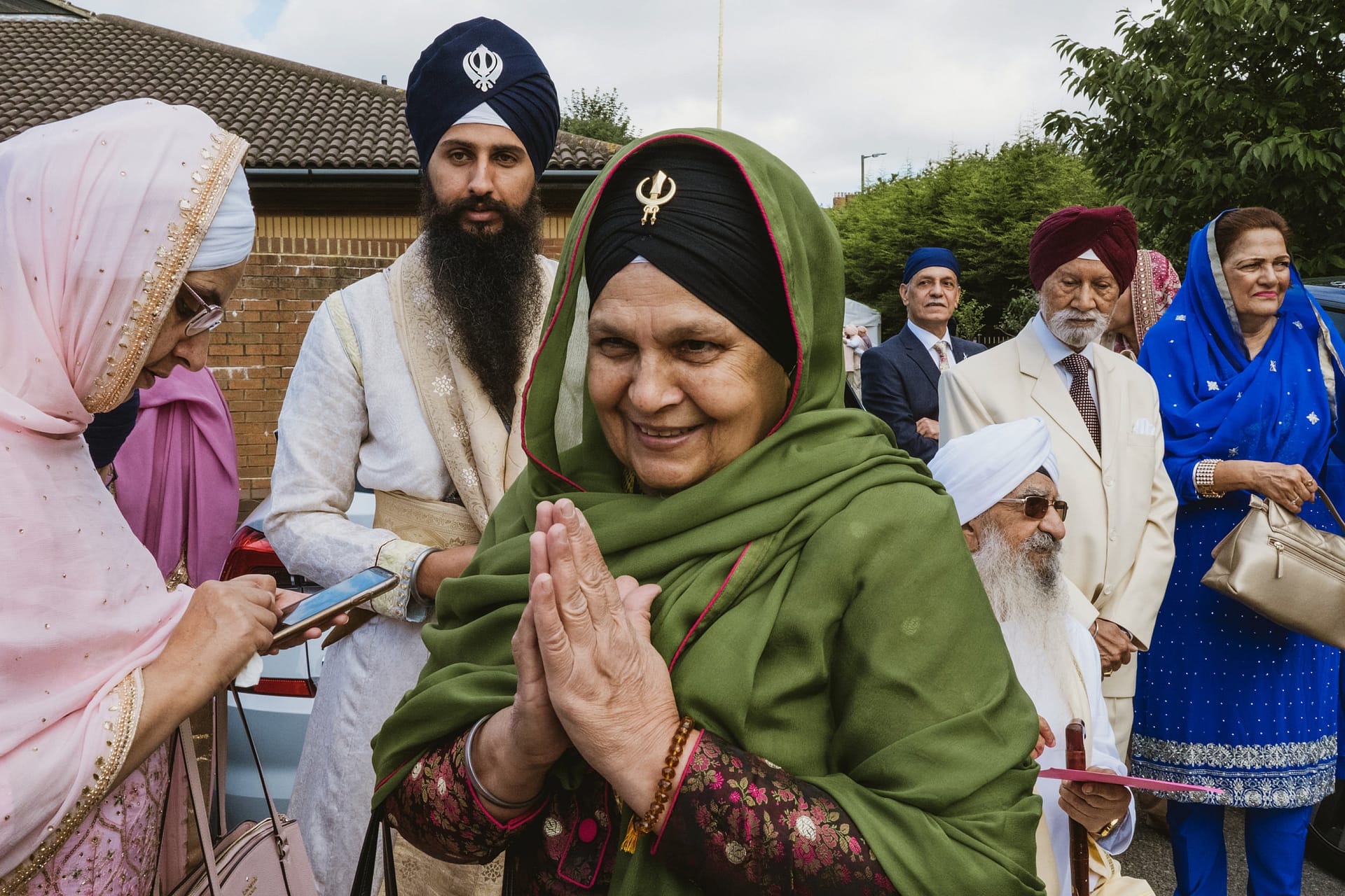 Sikh community gathering in traditional attire outdoors.