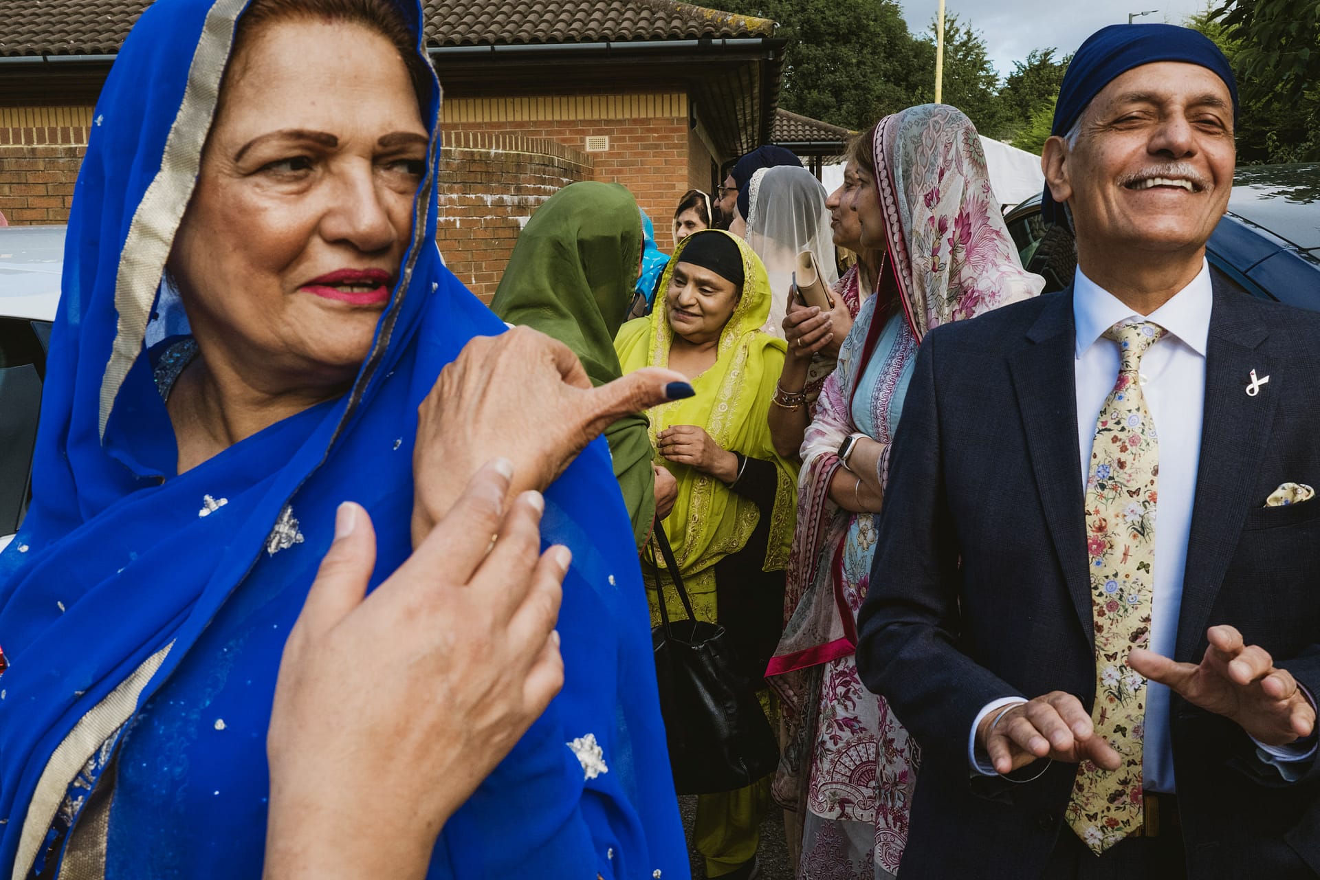 Group of people, colourful traditional attire, smiling outdoors.