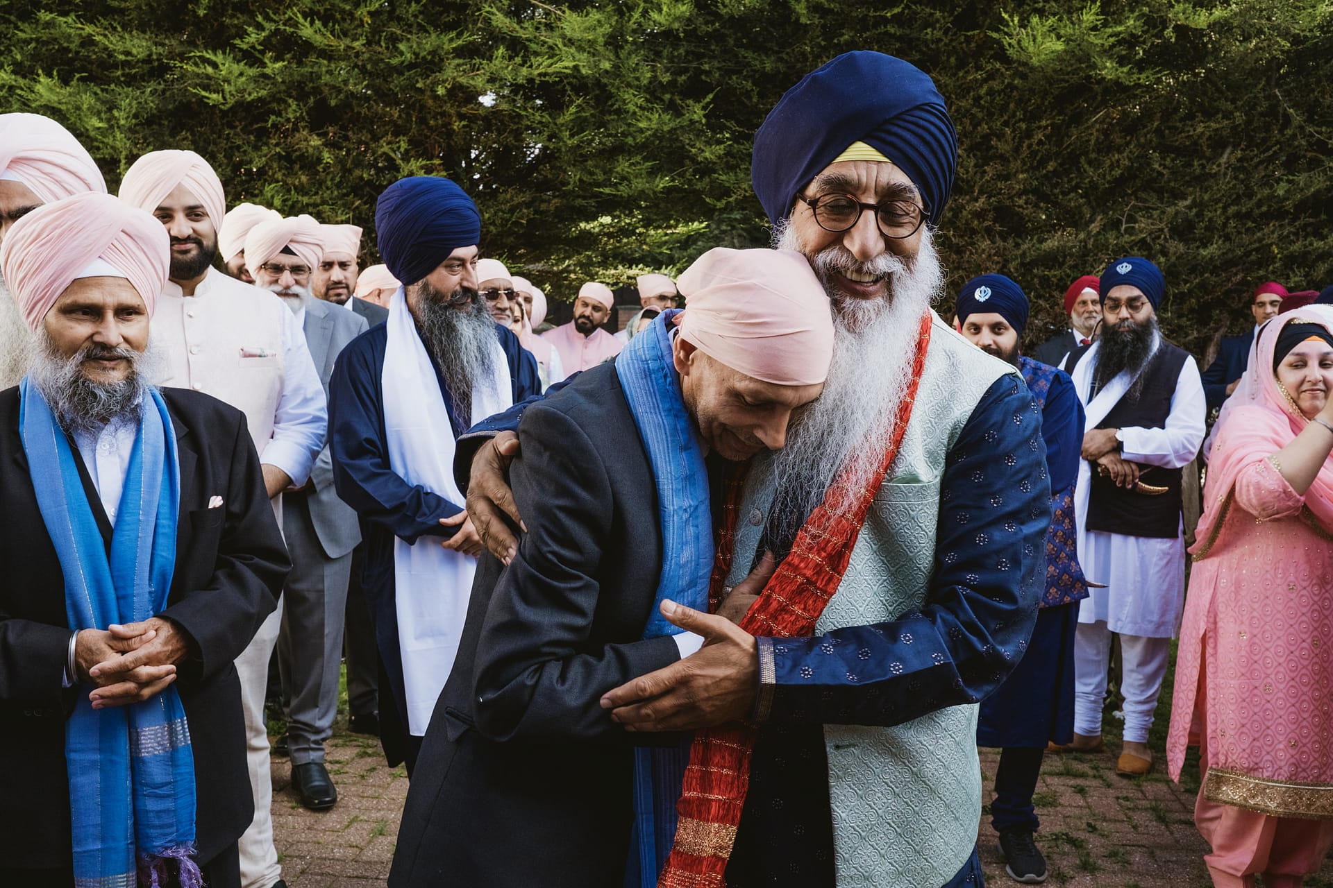 Group of men in traditional Sikh attire, embracing.