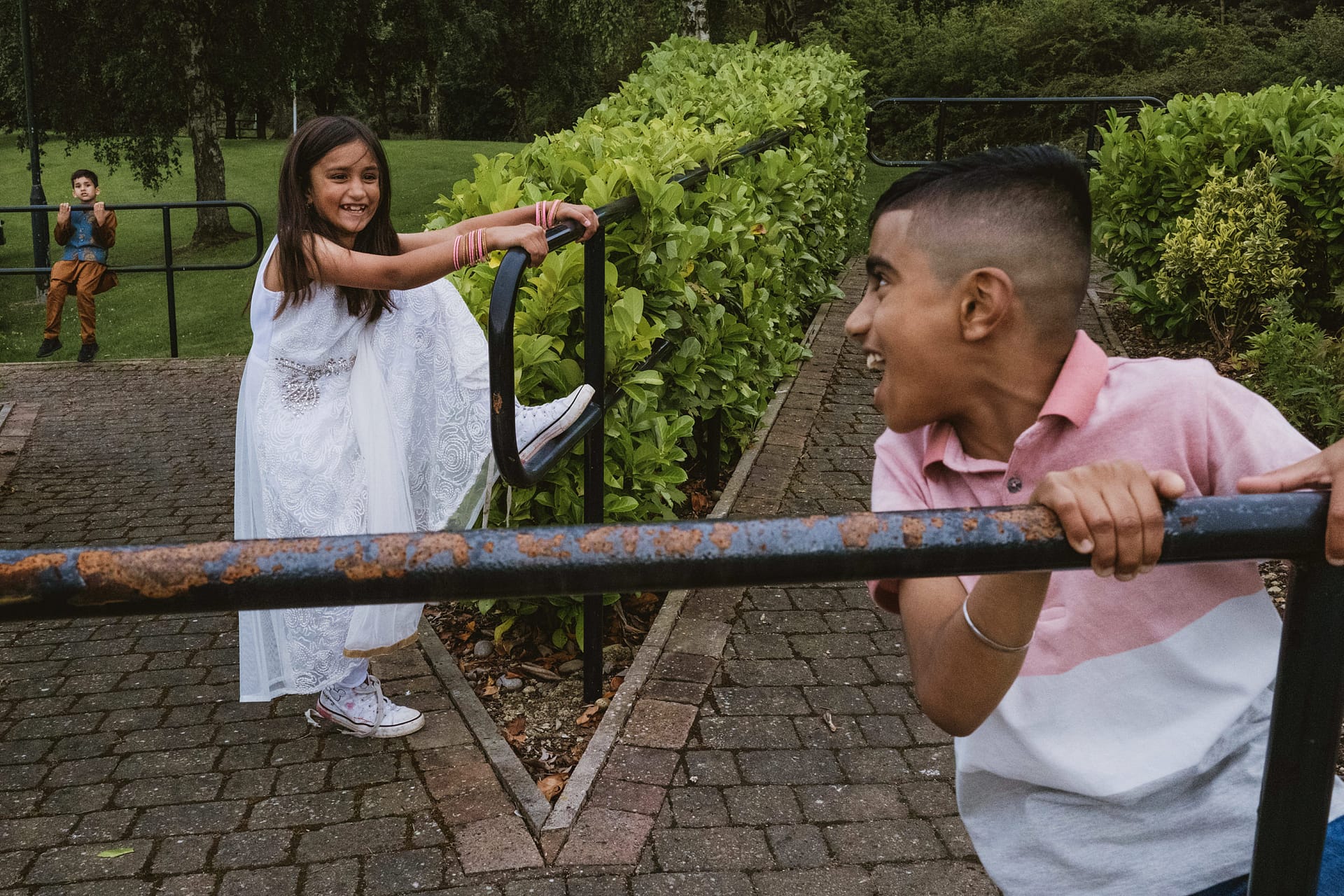 Children playing on park railings, smiling and laughing.