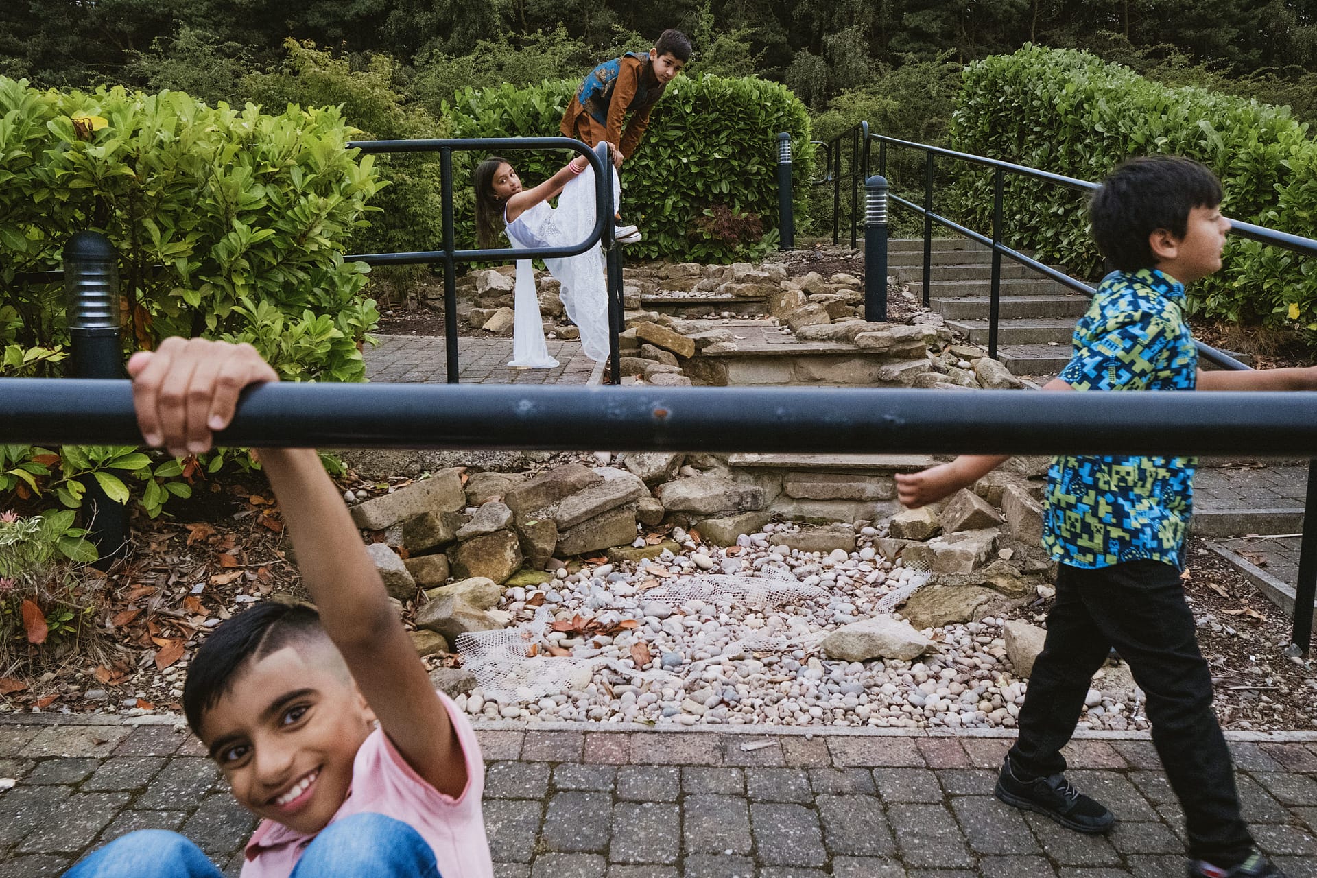 Children playing on railings in a garden setting.