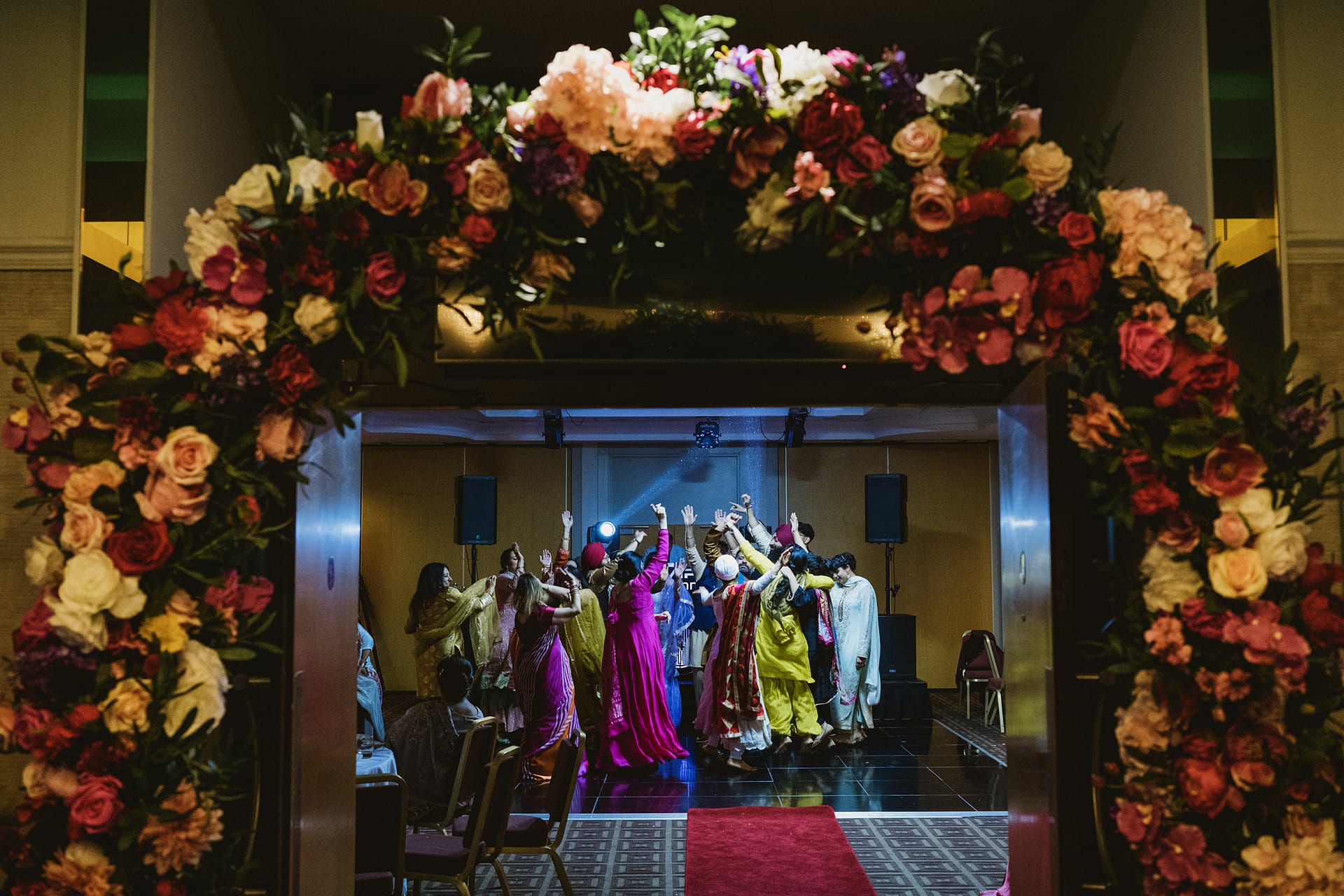 Vibrant dance party under floral archway.