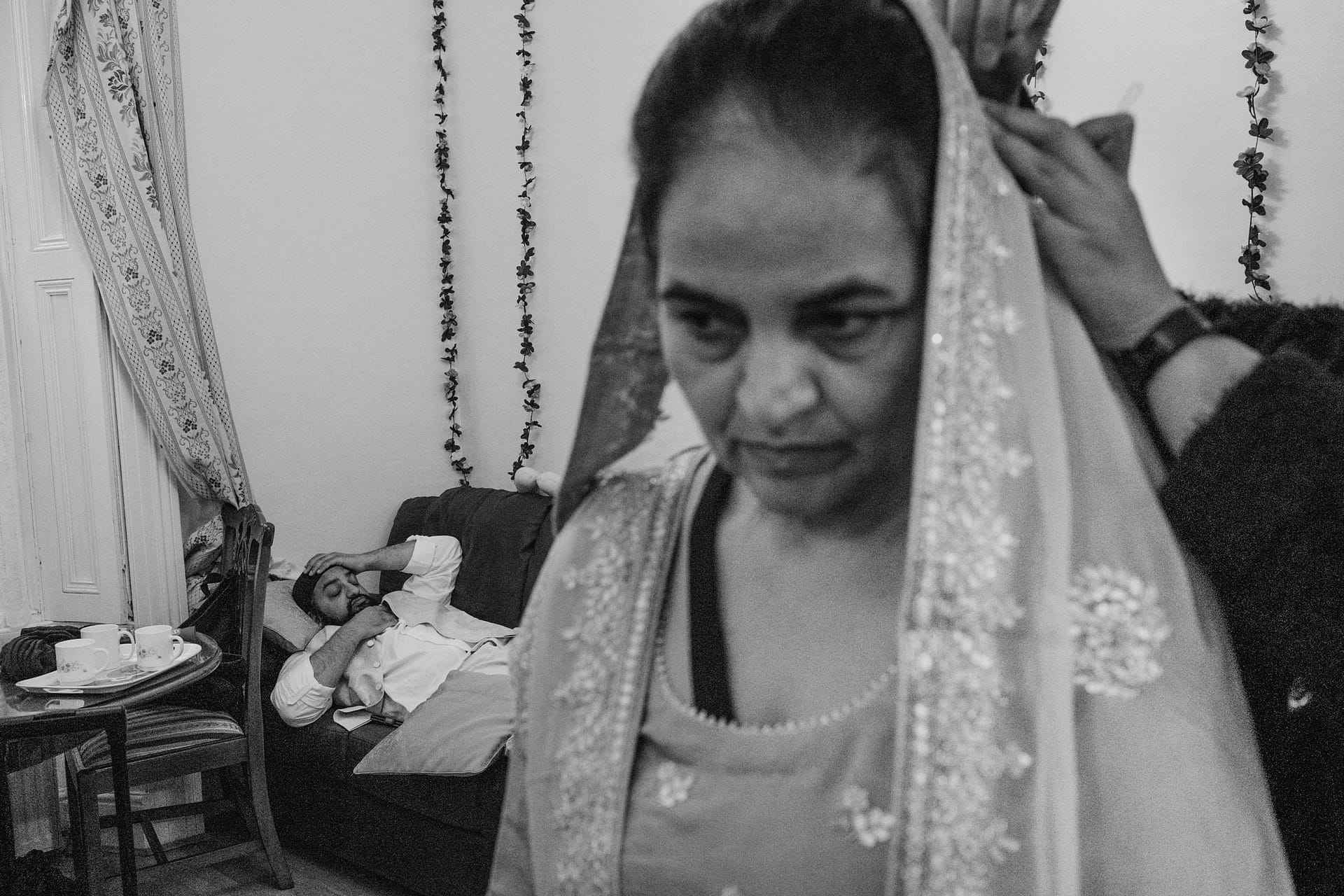 Woman in traditional attire, man resting on sofa.