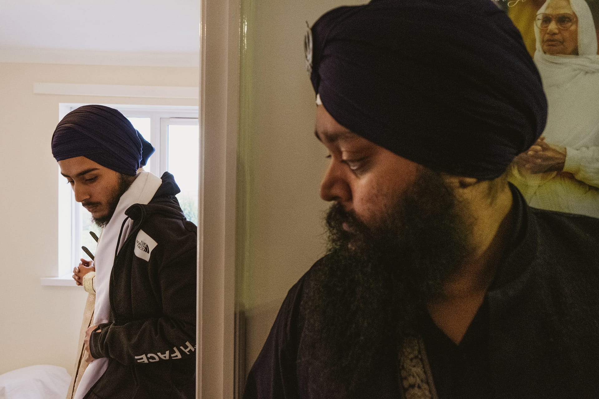 Two men wearing turbans in reflective moment.