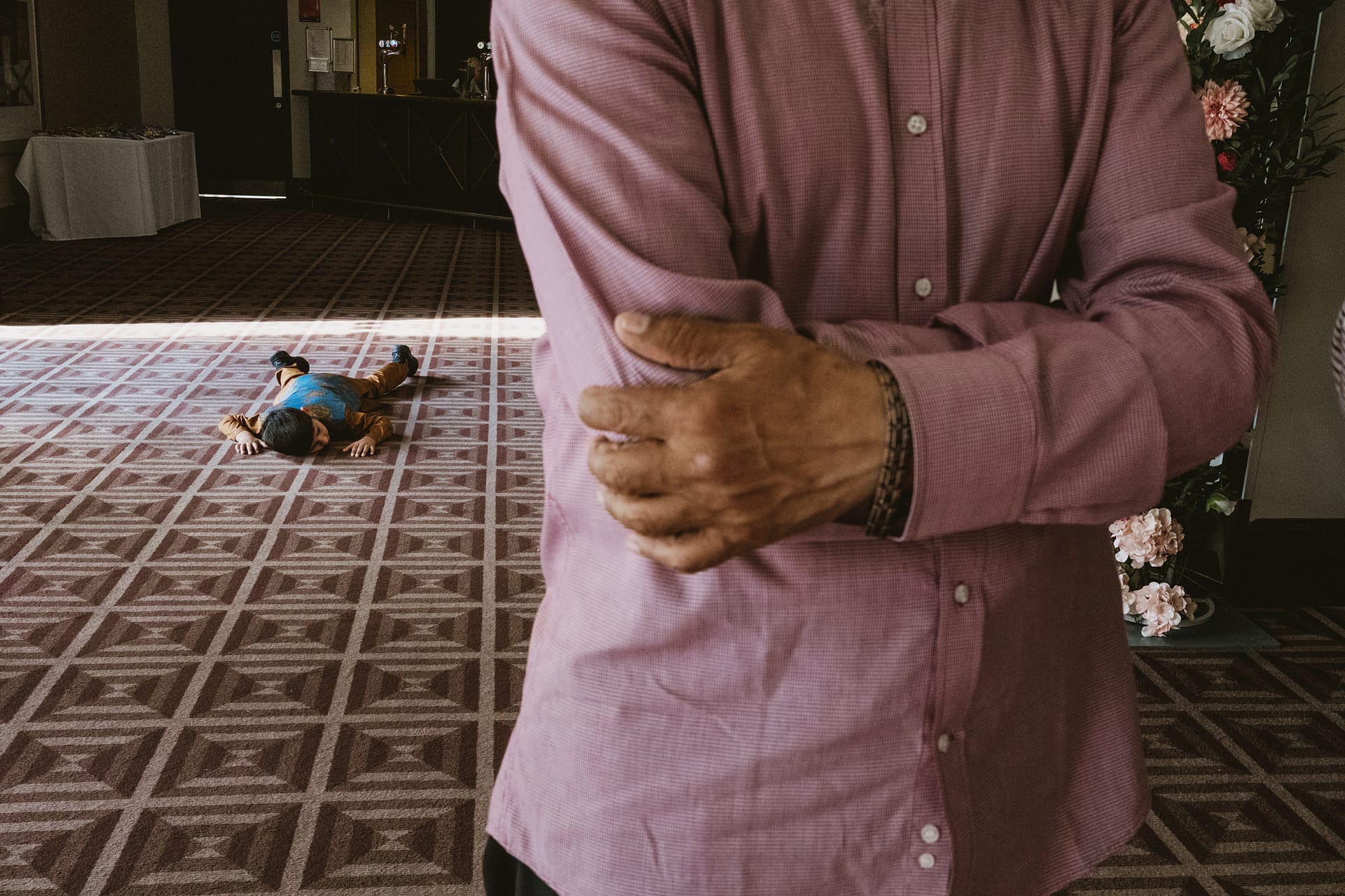 Person standing, child lying on patterned floor.