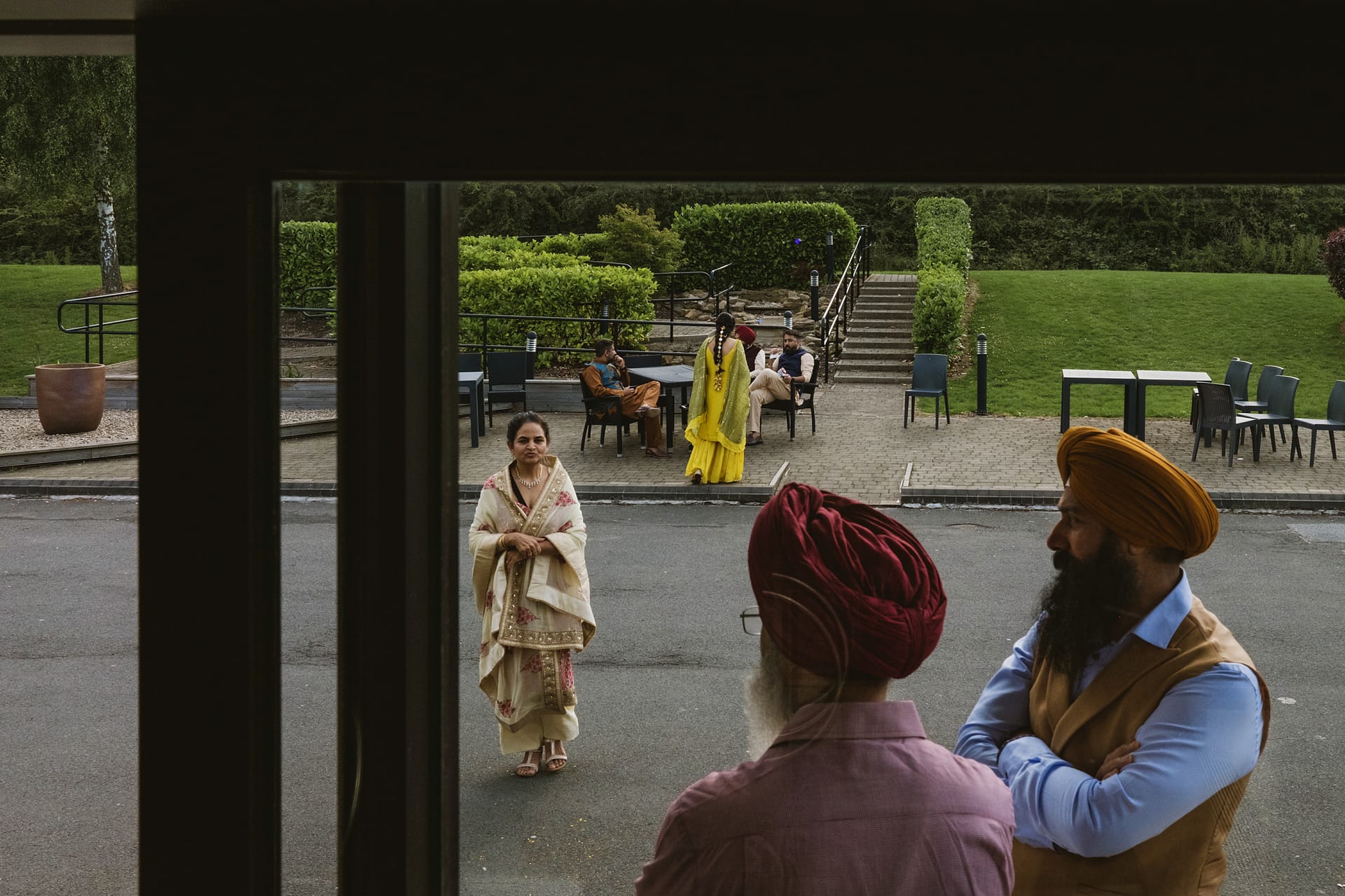 People gathering outdoors, lush garden background.