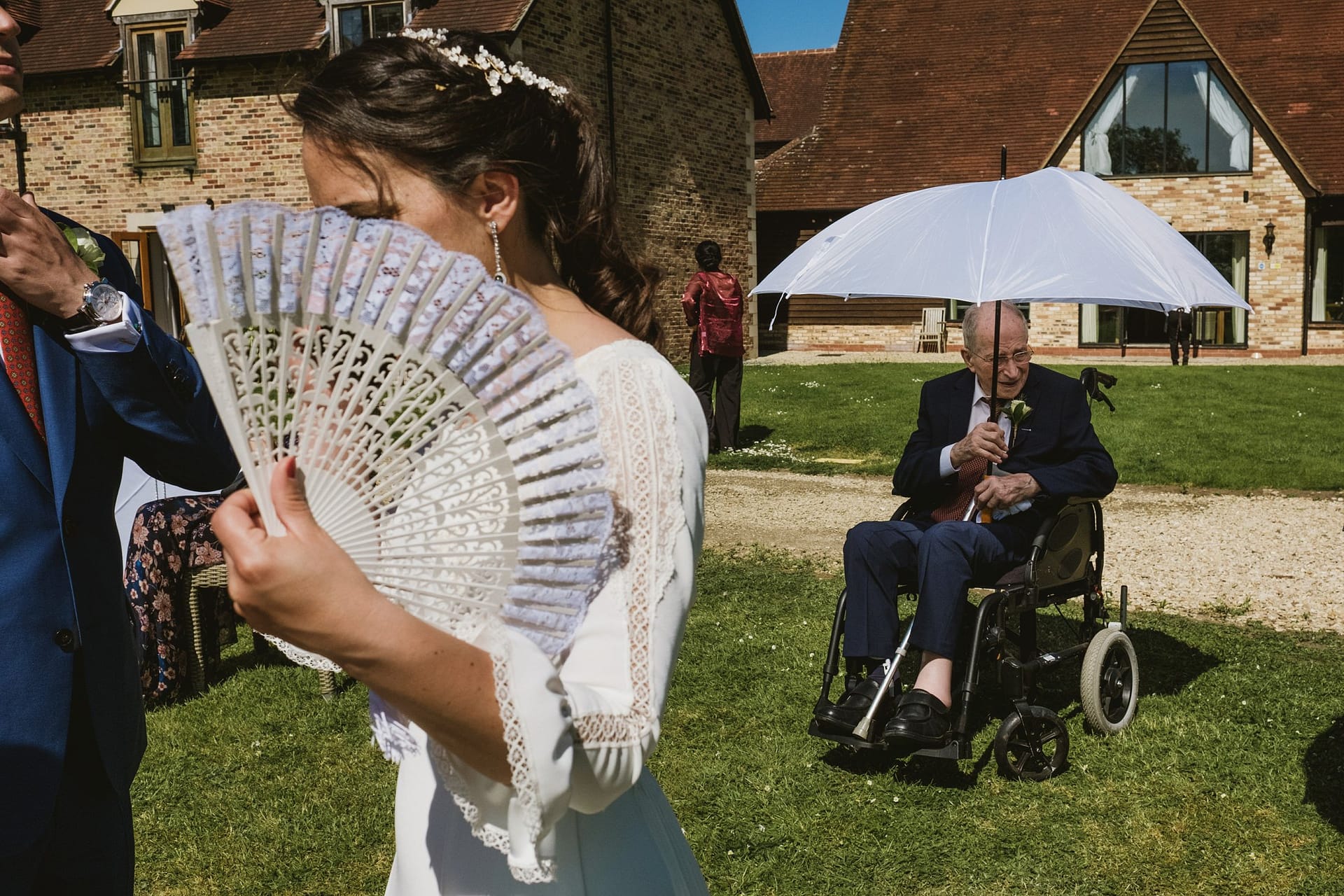 bride holding a white fan and an elderly gentlemen in the background at Voco Oxford Thames