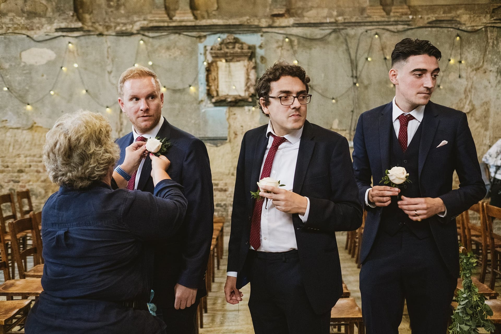 groomsmen putting on their button holes at asylum chapel