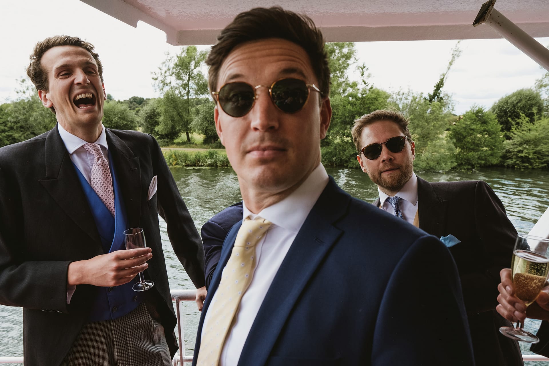 Men in suits on a boat, holding drinks.