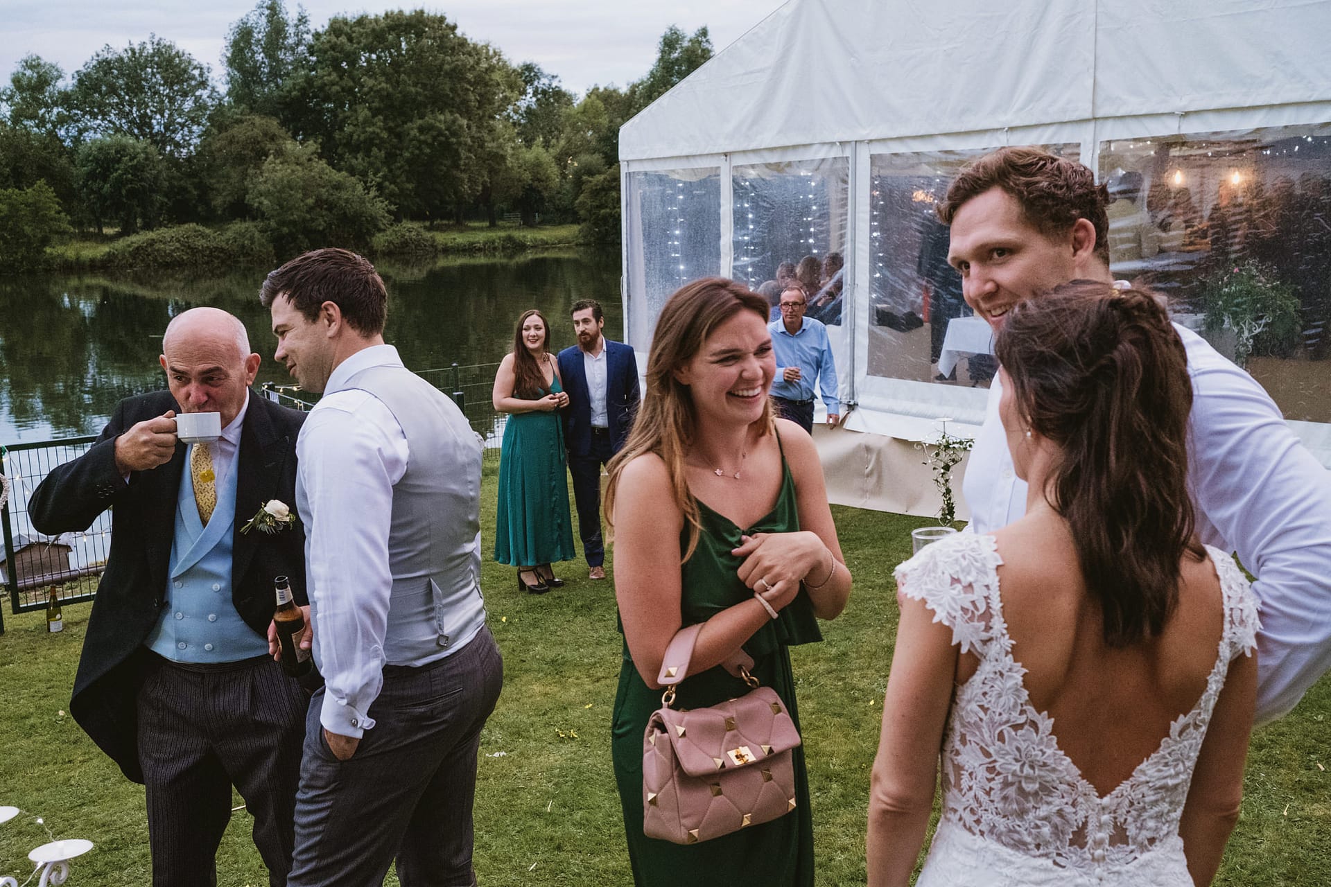 Guests enjoying outdoor wedding reception by lake