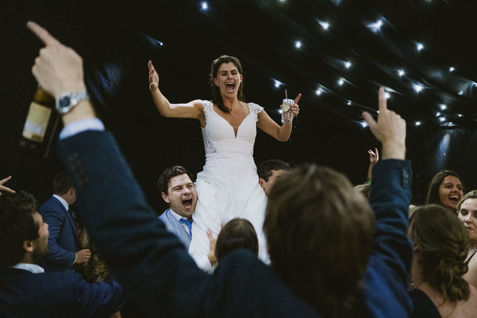 Bride celebrating on shoulders at wedding reception
