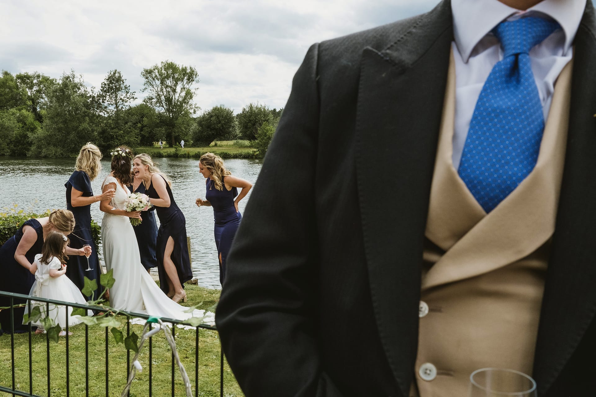 Bride with bridesmaids near lake at wedding.