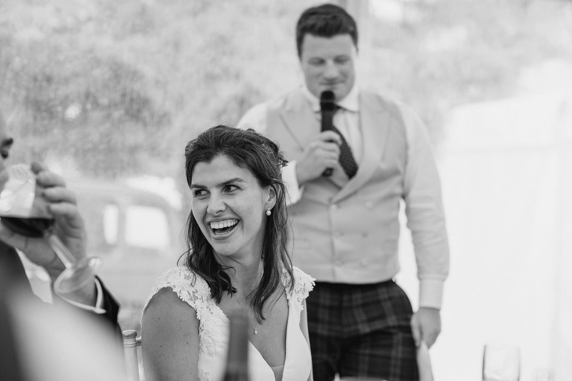 Bride smiling during wedding toast.