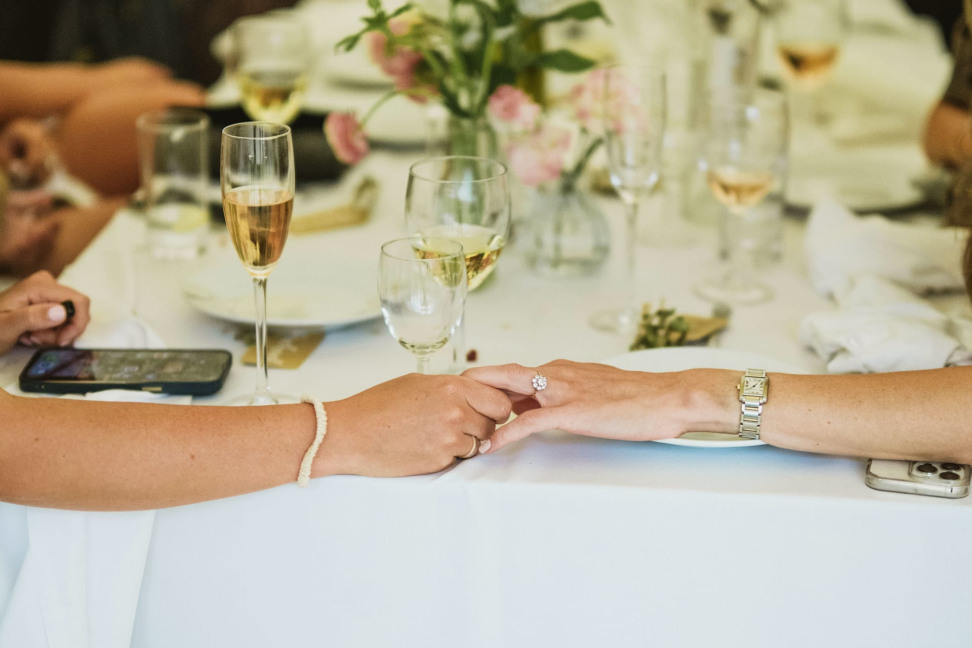 Couple holding hands at table with champagne