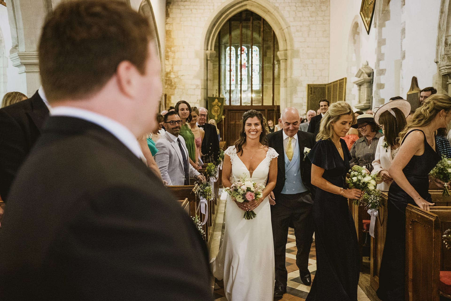 Bride walking down church aisle with guests.