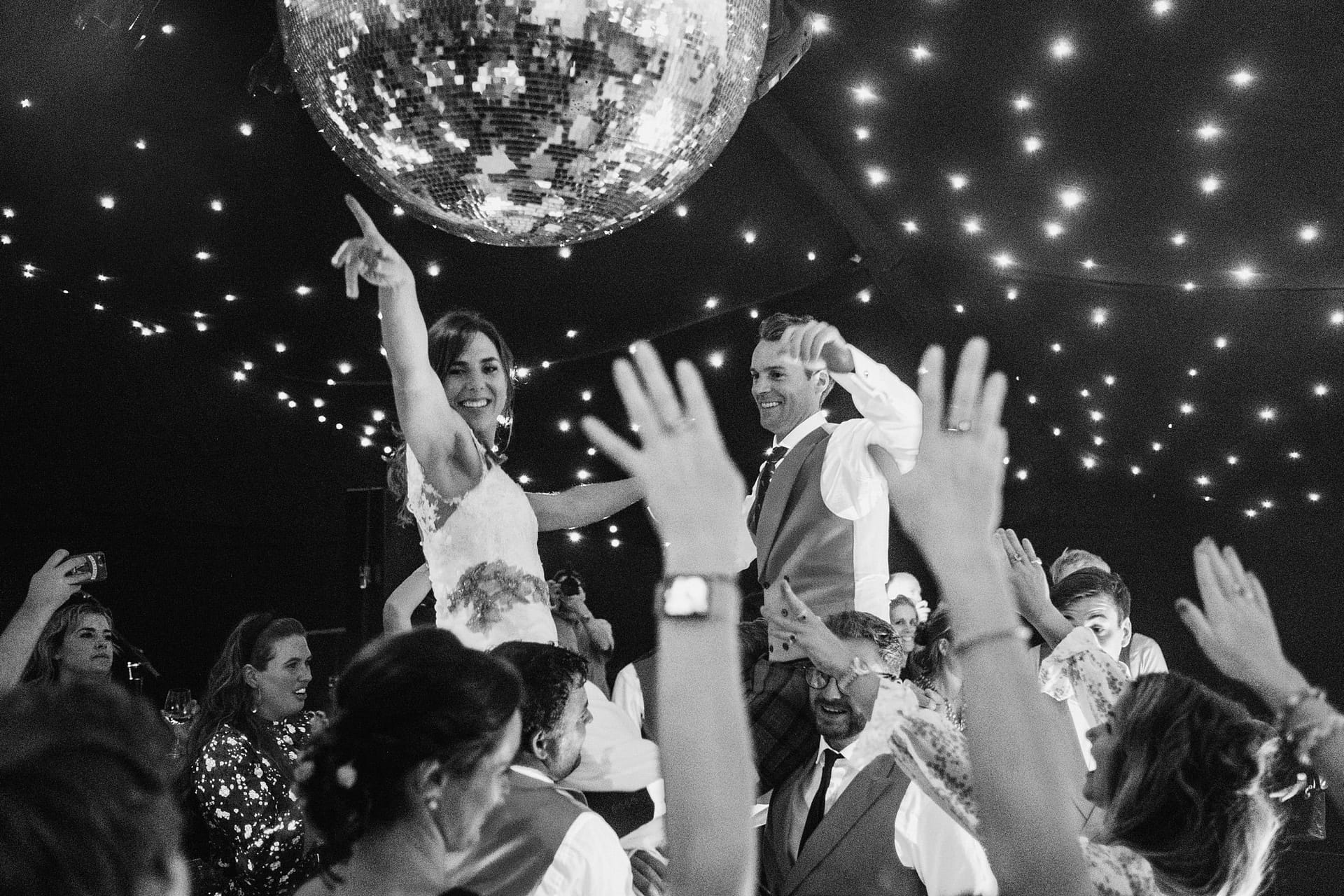 bride and groom being lifted in the air on the dance floor