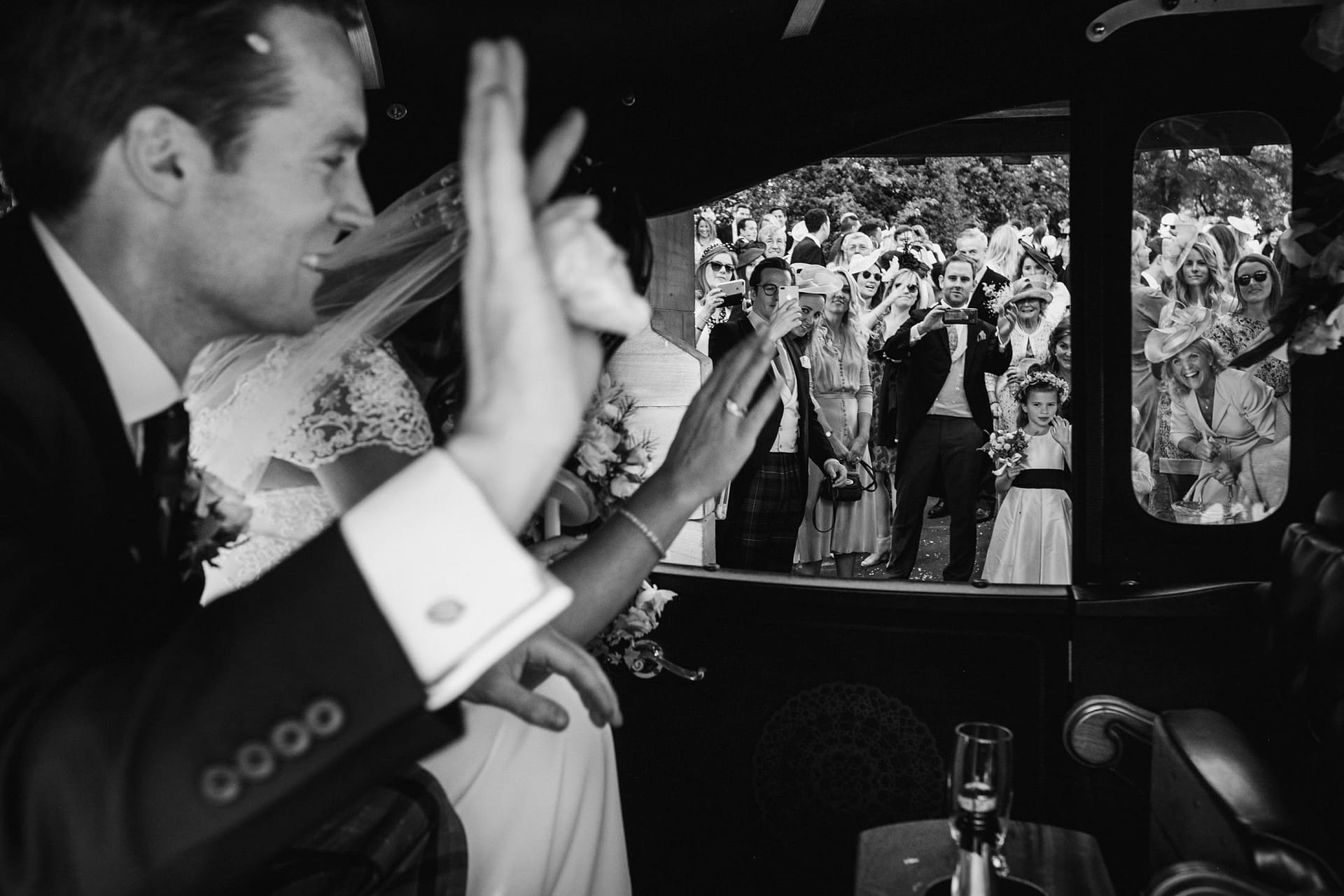 bride and groom waving their guests off in the wedding car in Cheshire