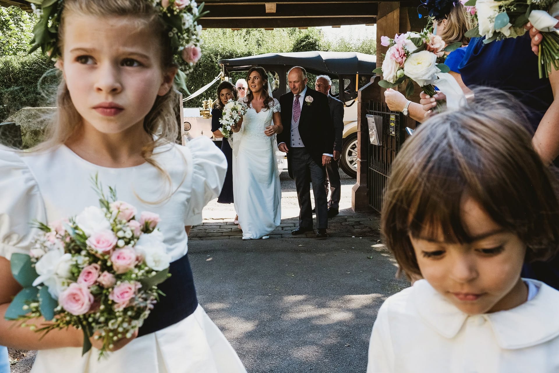 bride and wedding party arriving at church with flower girl and page boy in foreground.
