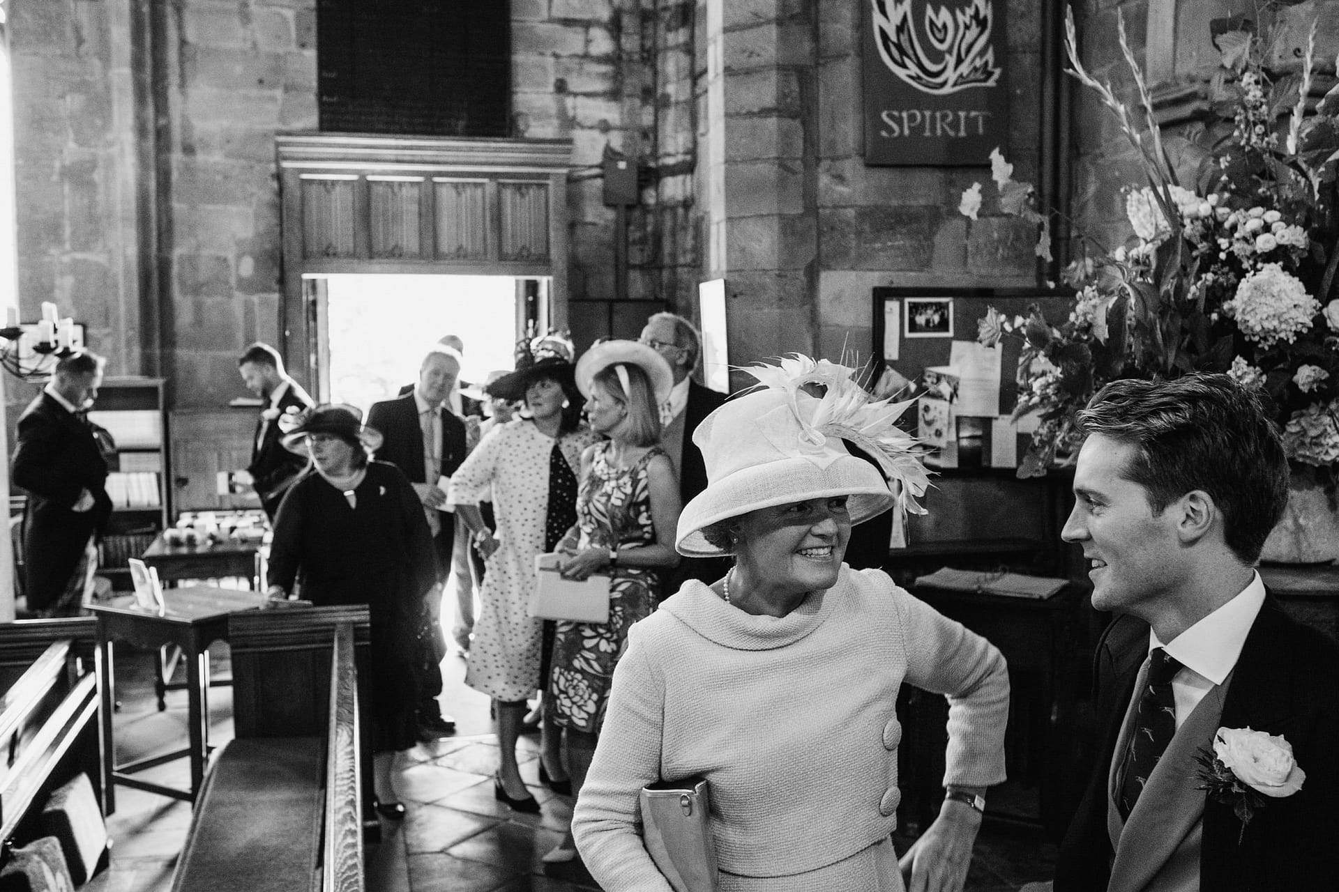 Wedding guests arriving at the church, guest talking to groom.