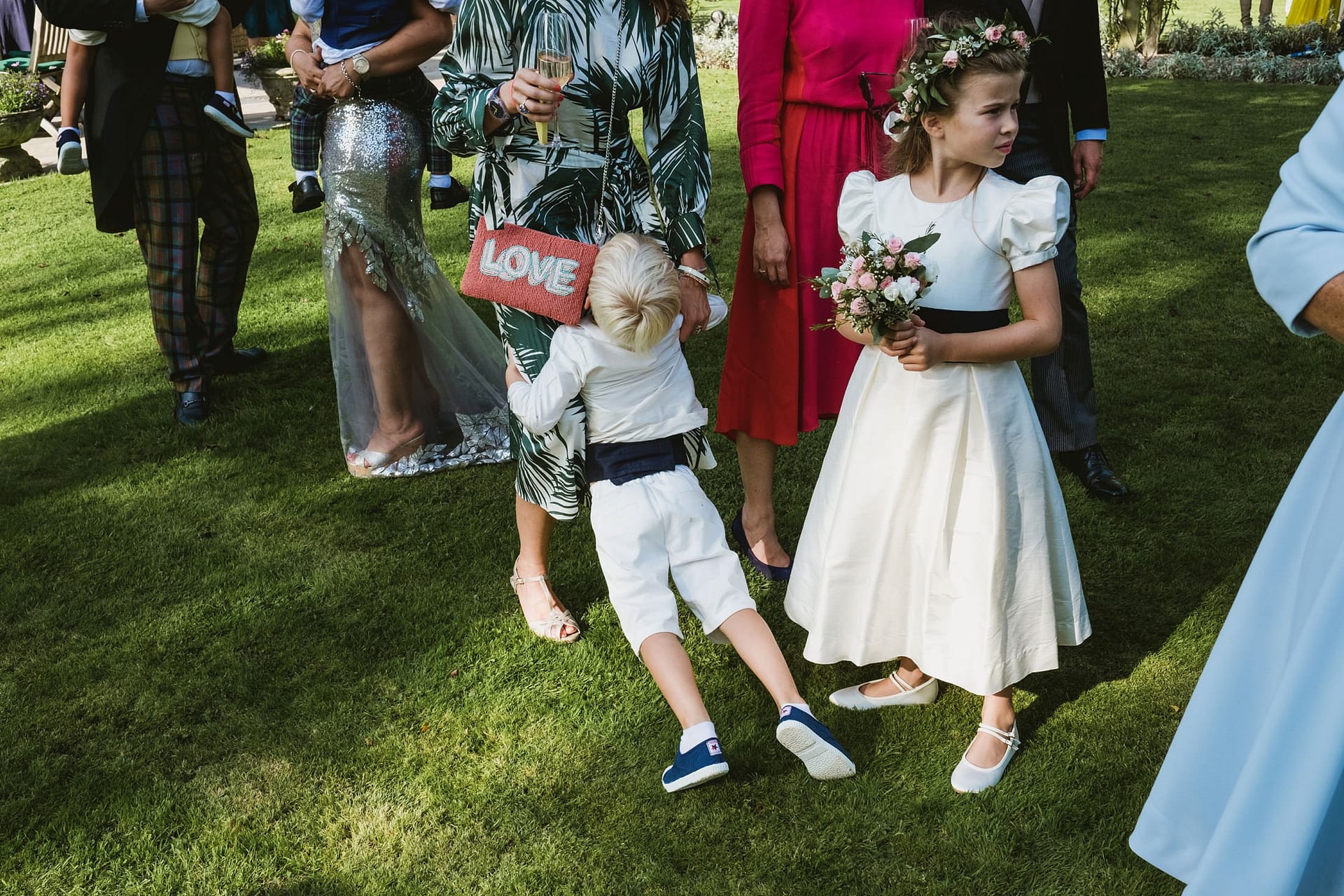 page boy leaning on his mum bored with flower girl next to them