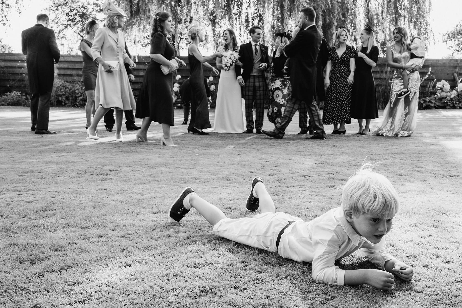 page boy on grass whilst wedding group is rearranged