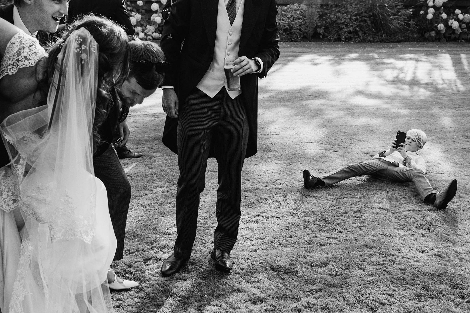 page boy lying on grass taking a photo