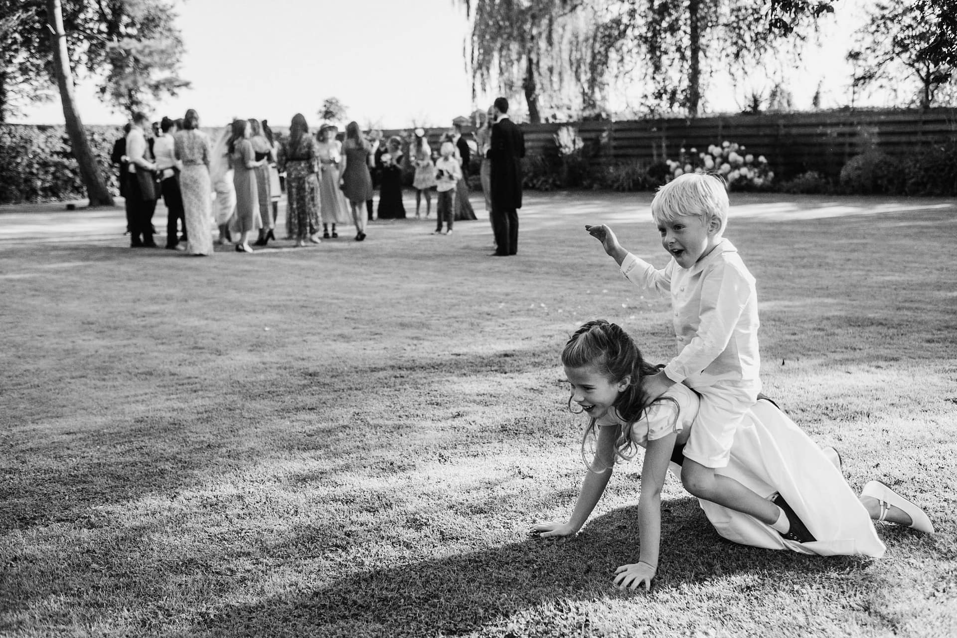 page boy on flower girl's back, whilst wedding group take place in a Cheshire wedding venue