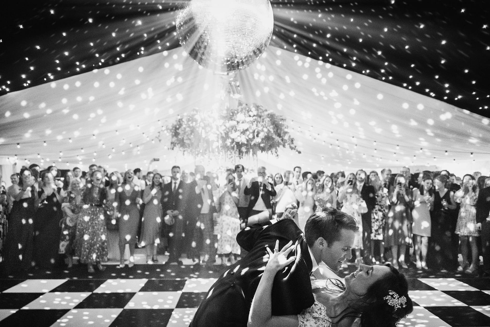 bride and groom first dance, groom dipping the bride with mirror ball