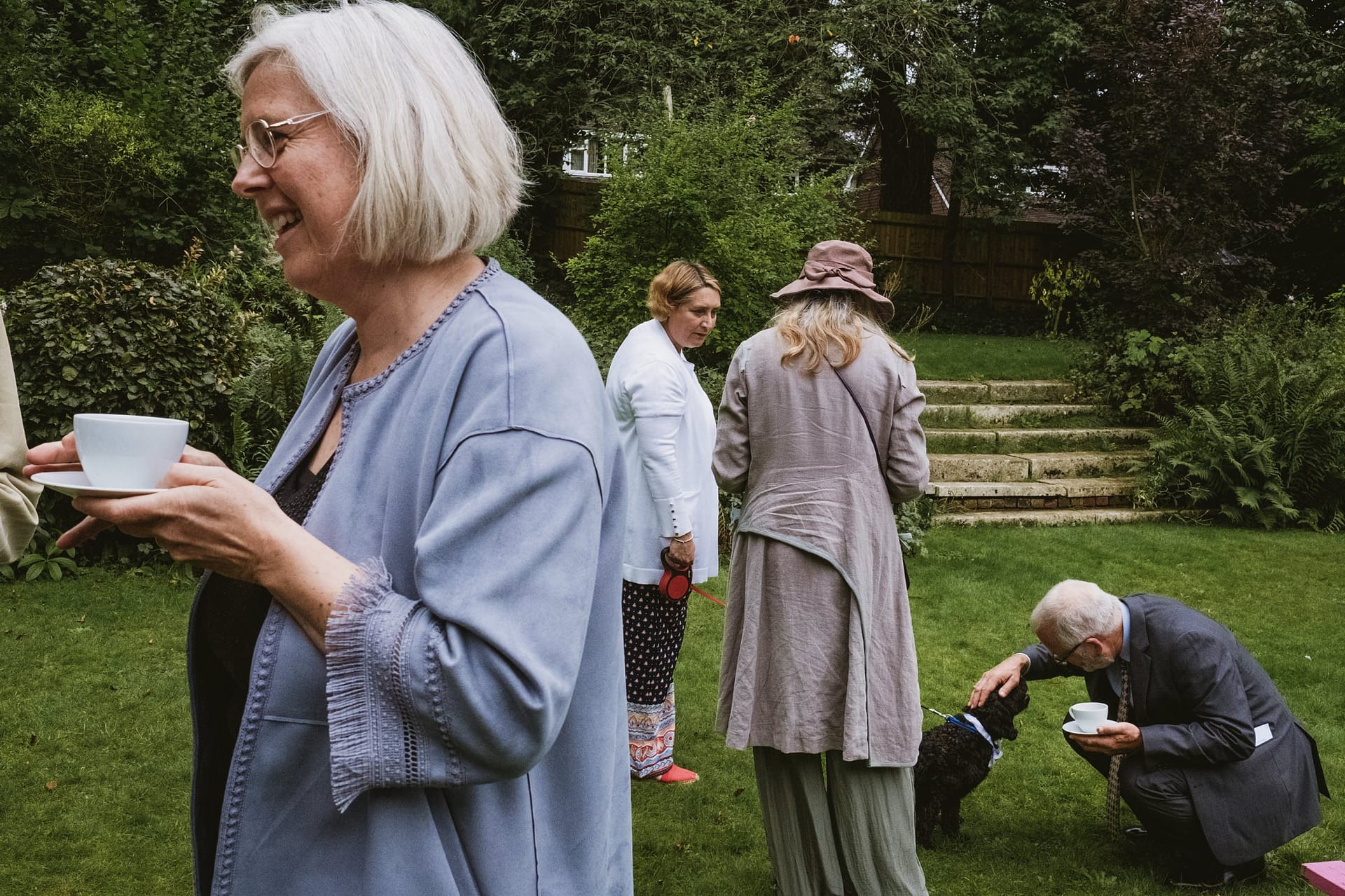 guest patting dog with other guest drinking coffee in foreground