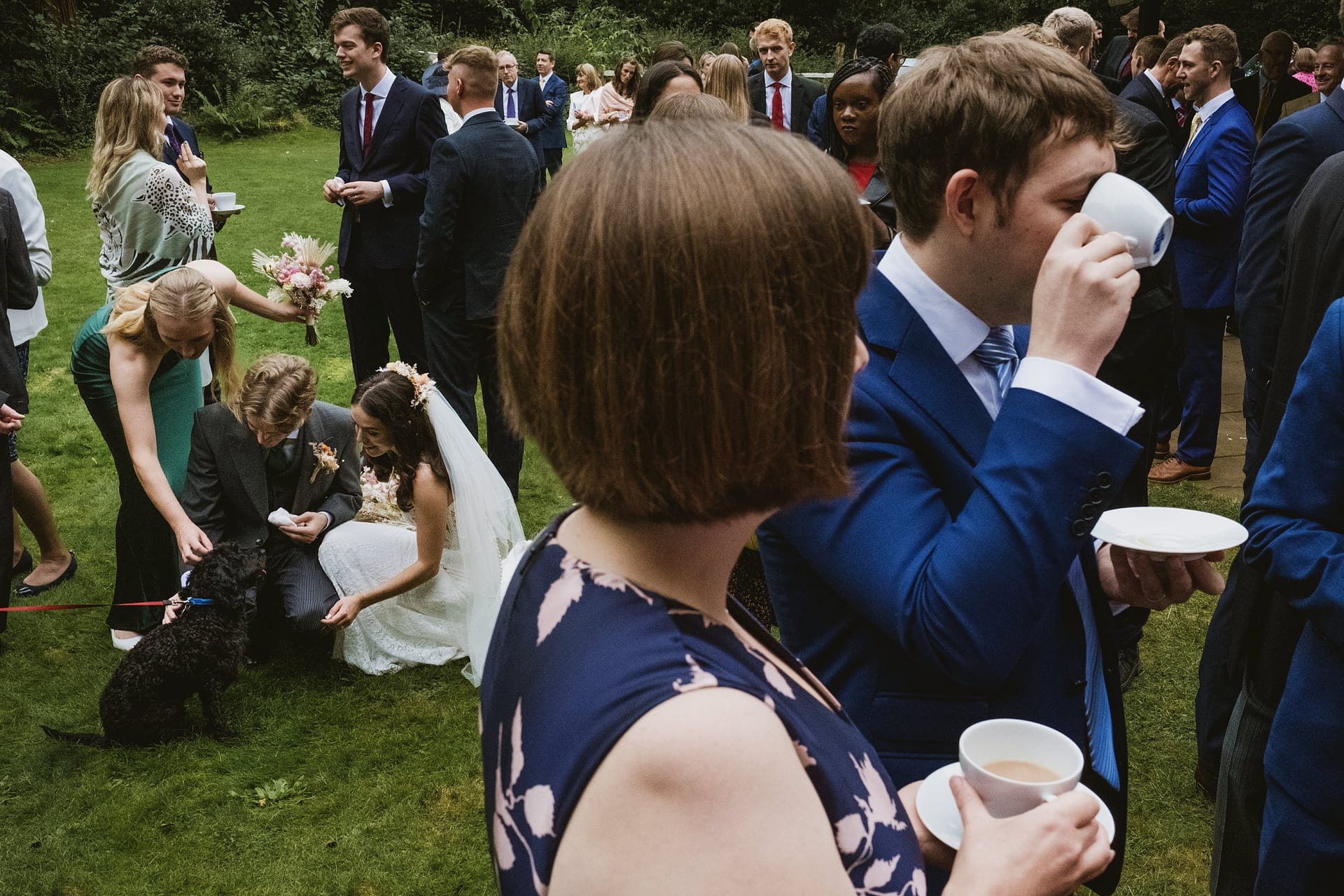 bride stroking the dog with guests drinking coffee and tea in foreground