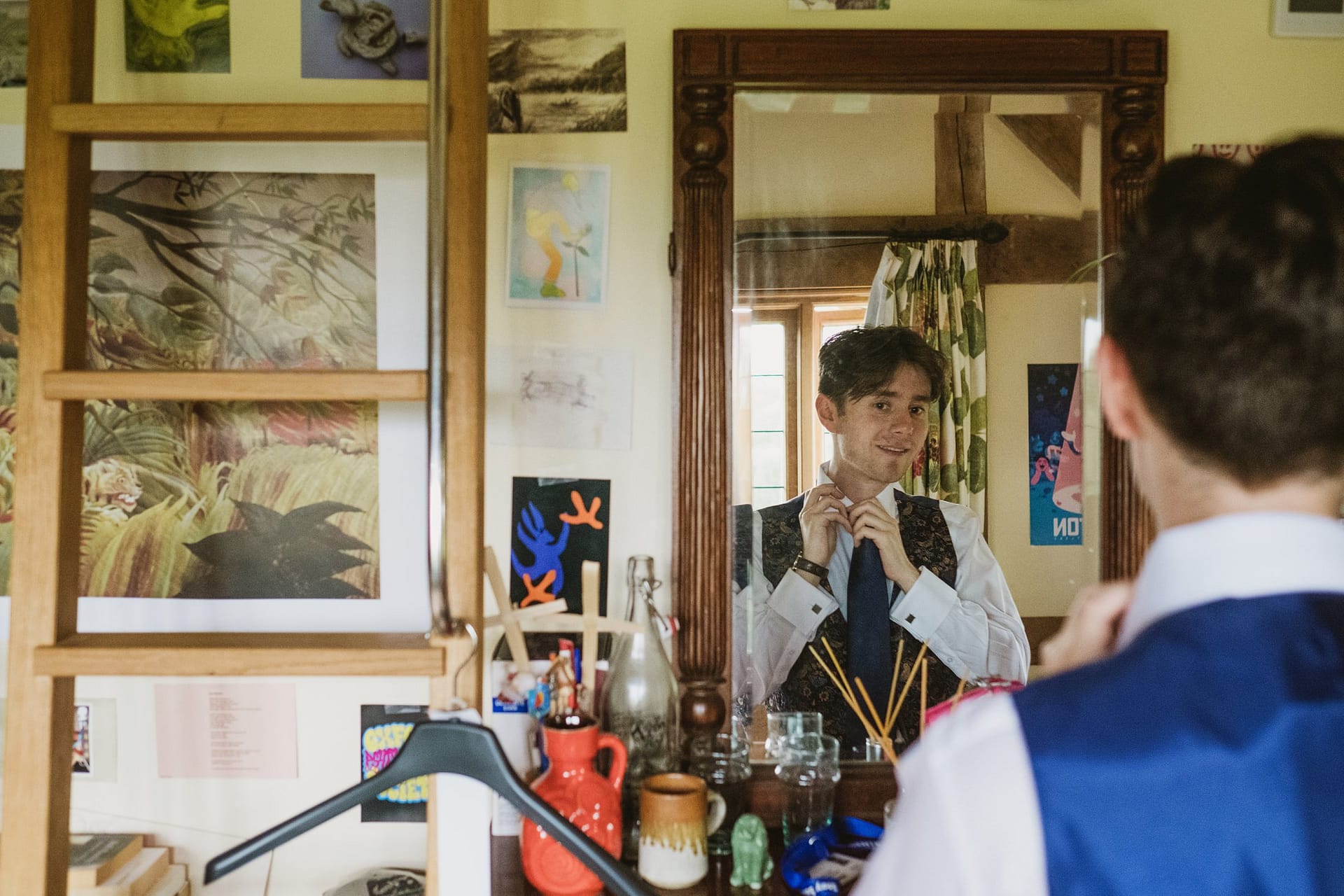 groom tying his tie in the mirror in Surrey
